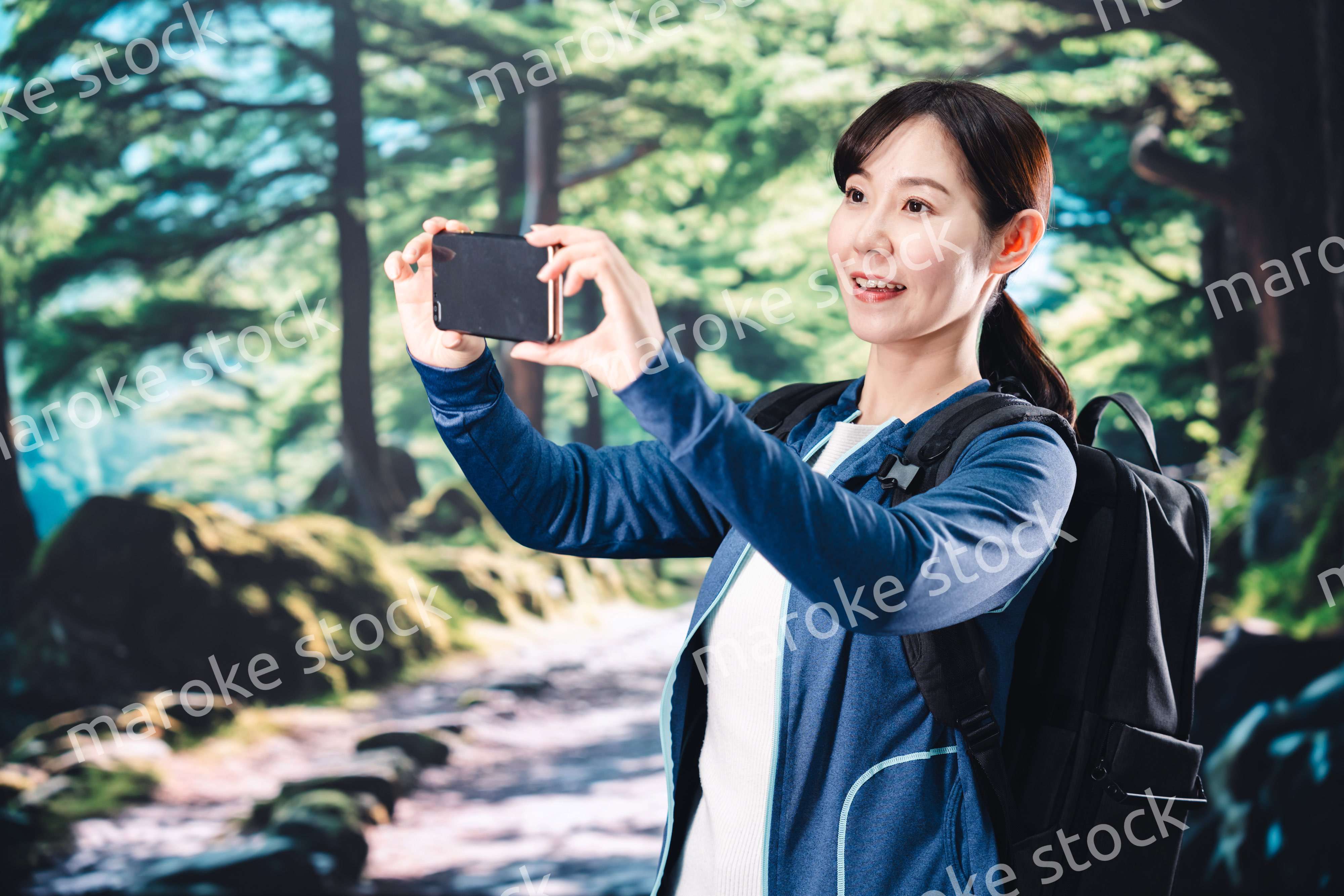 ハイキングをしながらスマホで写真を撮る若い女性