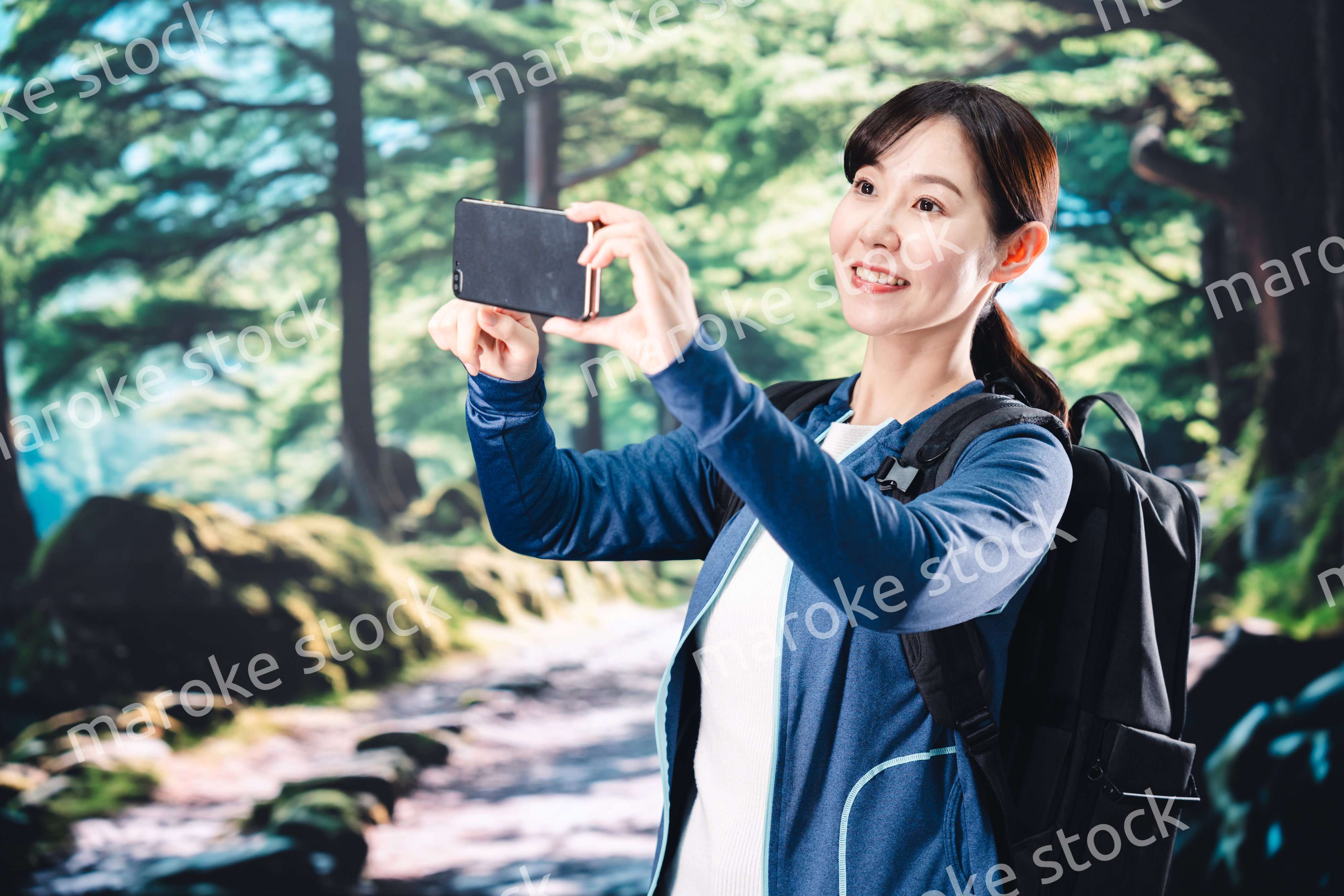 ハイキングをしながらスマホで写真を撮る若い女性