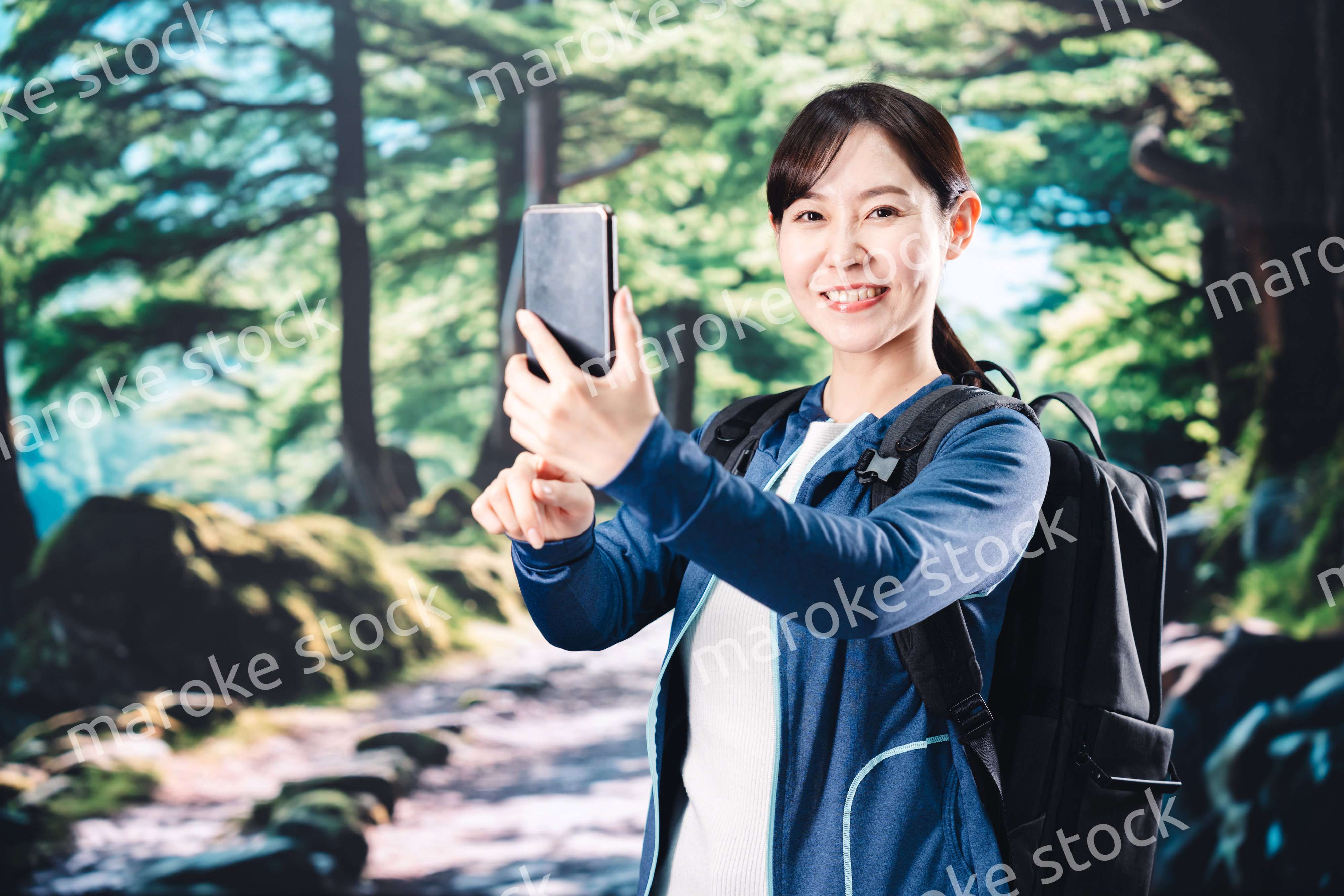 ハイキングをしながらスマホで写真を撮る若い女性