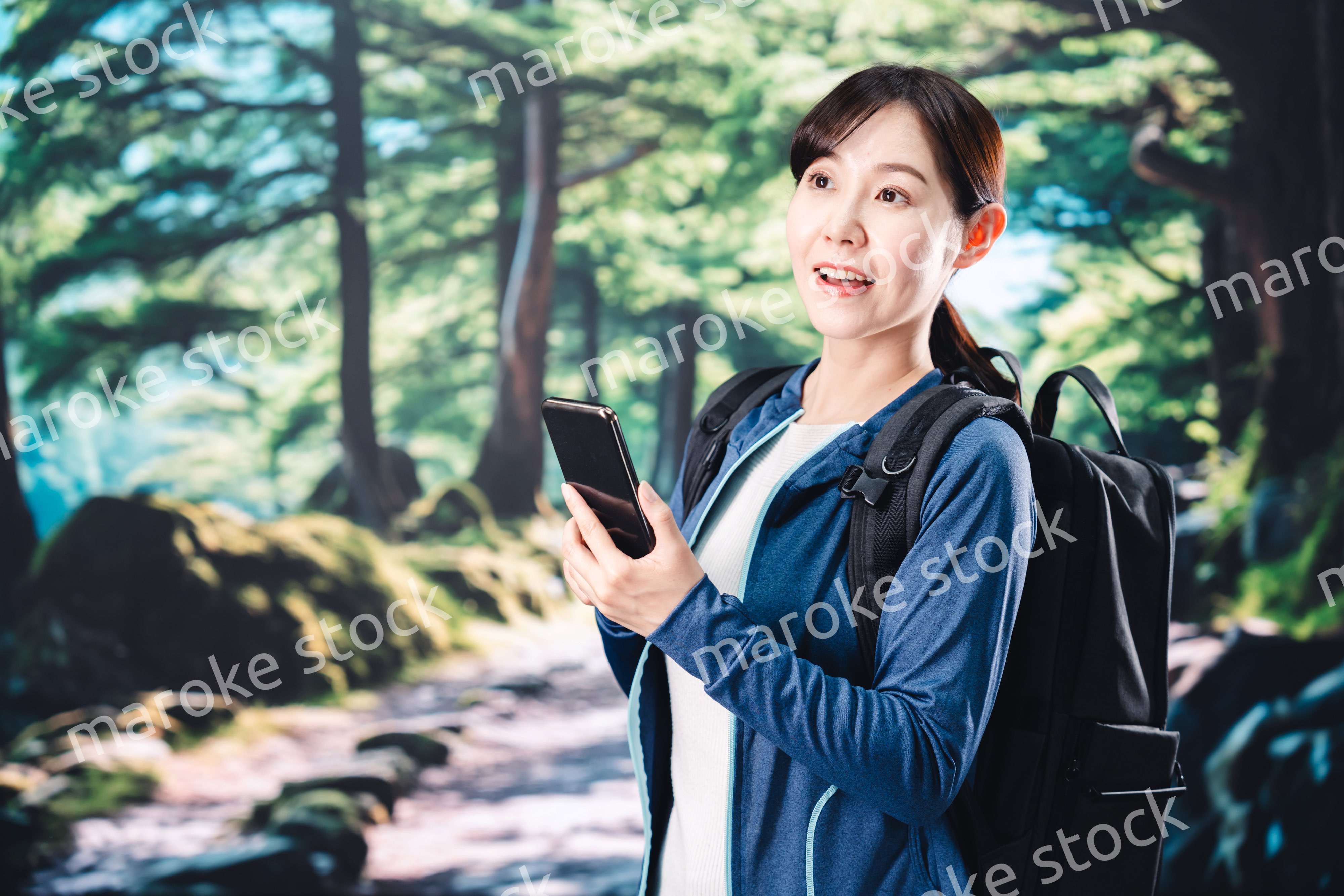 ハイキングをしながらスマホで写真を撮る若い女性