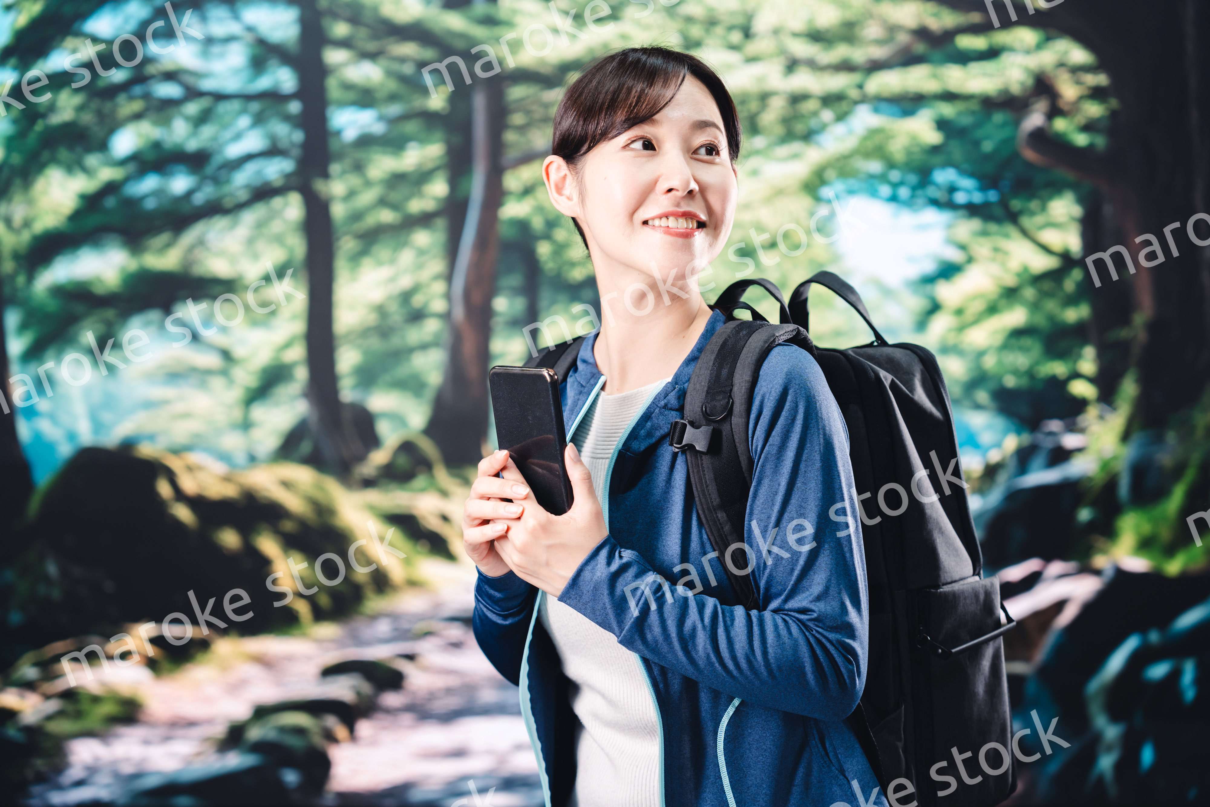 ハイキングをしながらスマホで写真を撮る若い女性