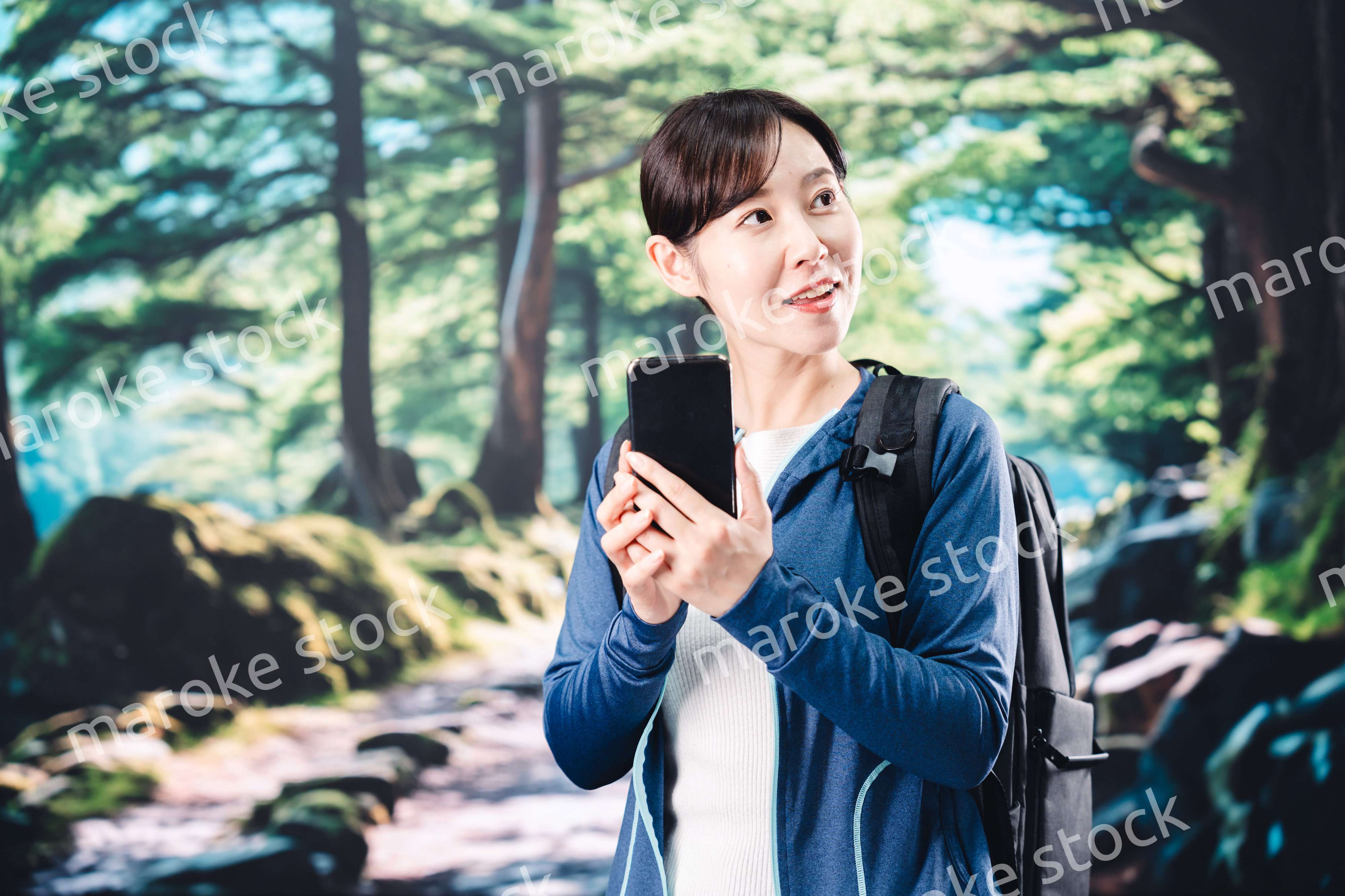 ハイキングをしながらスマホで写真を撮る若い女性