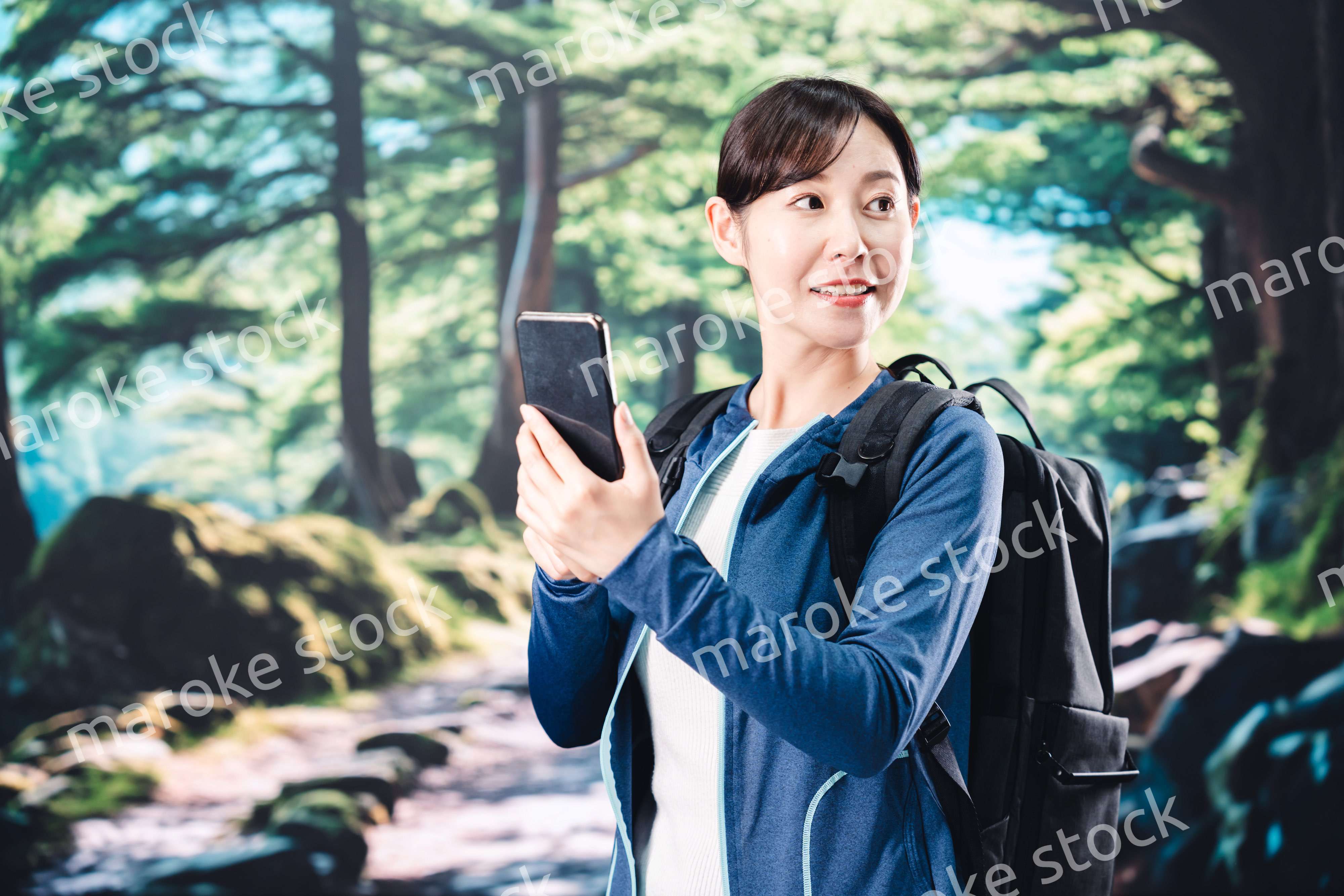 ハイキングをしながらスマホで写真を撮る若い女性