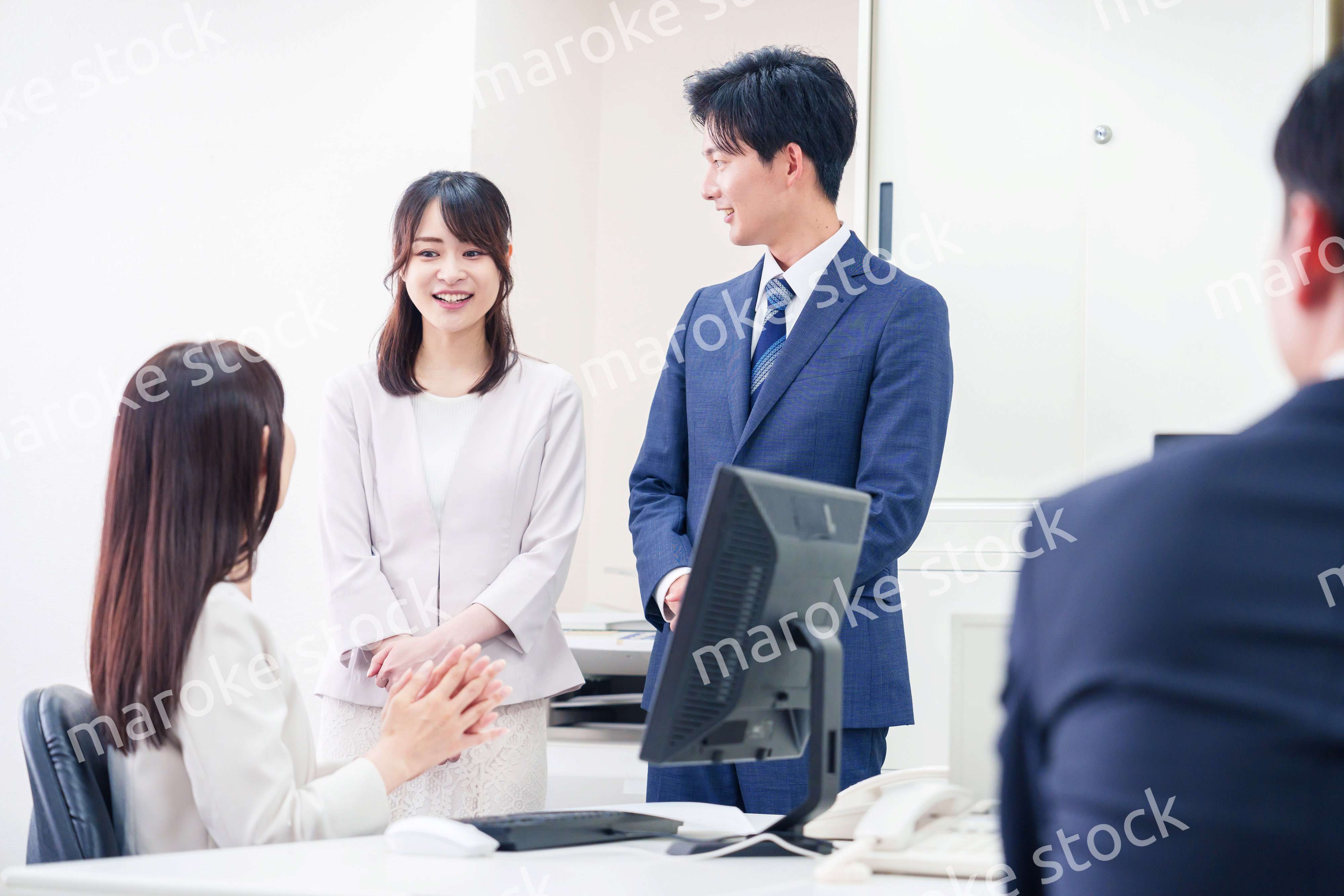 職場で上司に結婚の報告をするビジネスパーソンのカップル