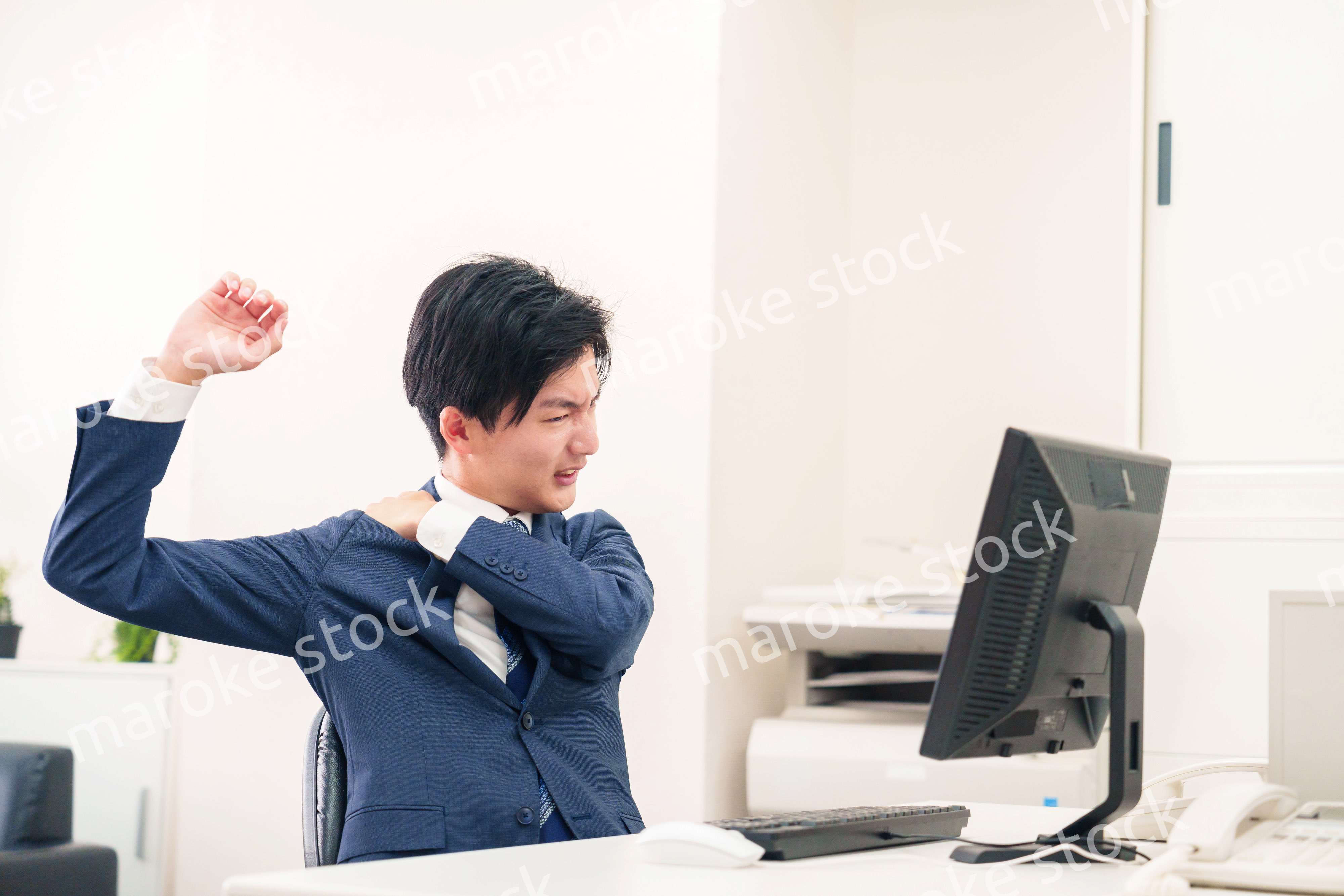 オフィスで肩こりに悩むビジネスマン
