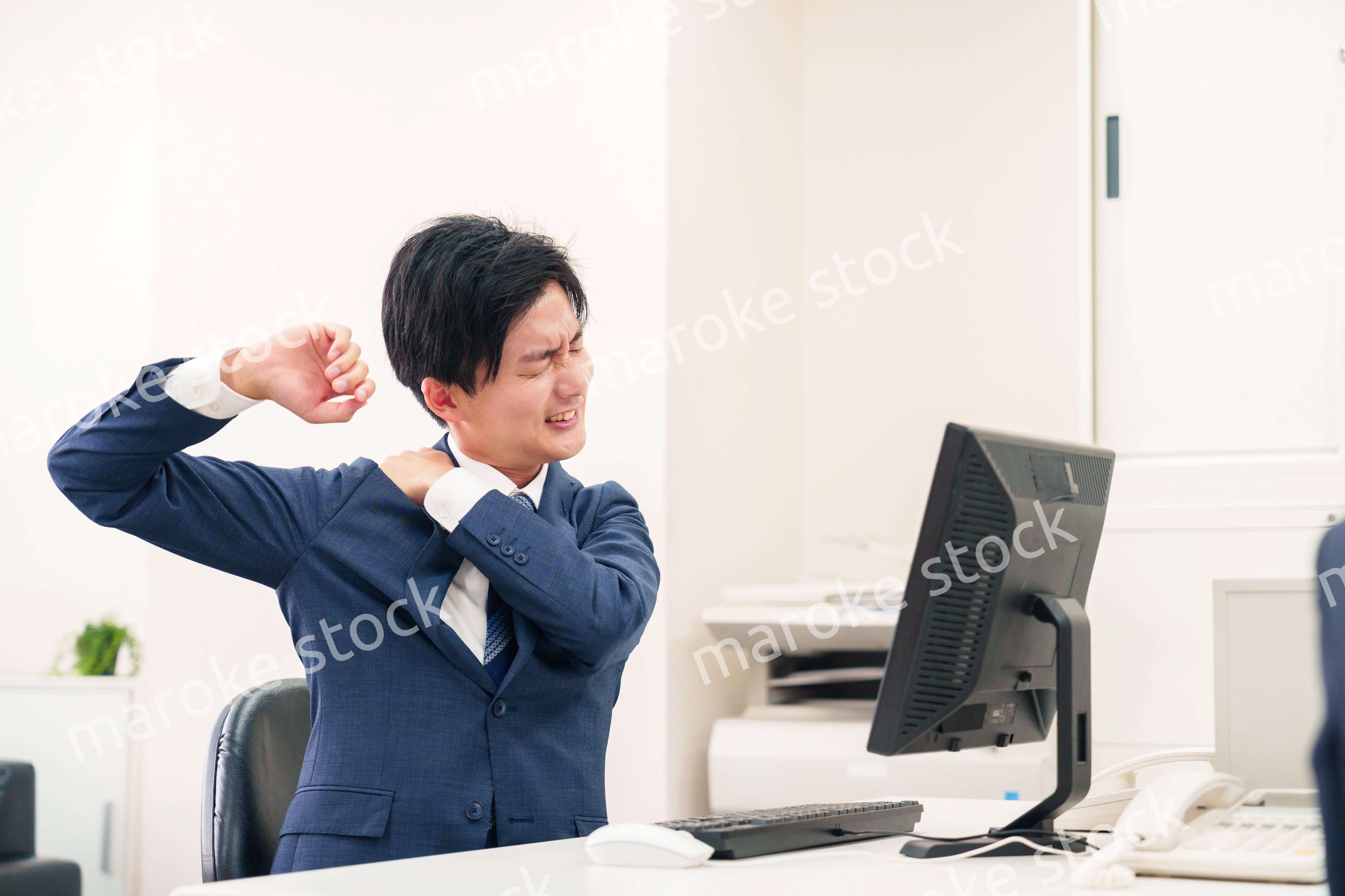 オフィスで肩こりに悩むビジネスマン