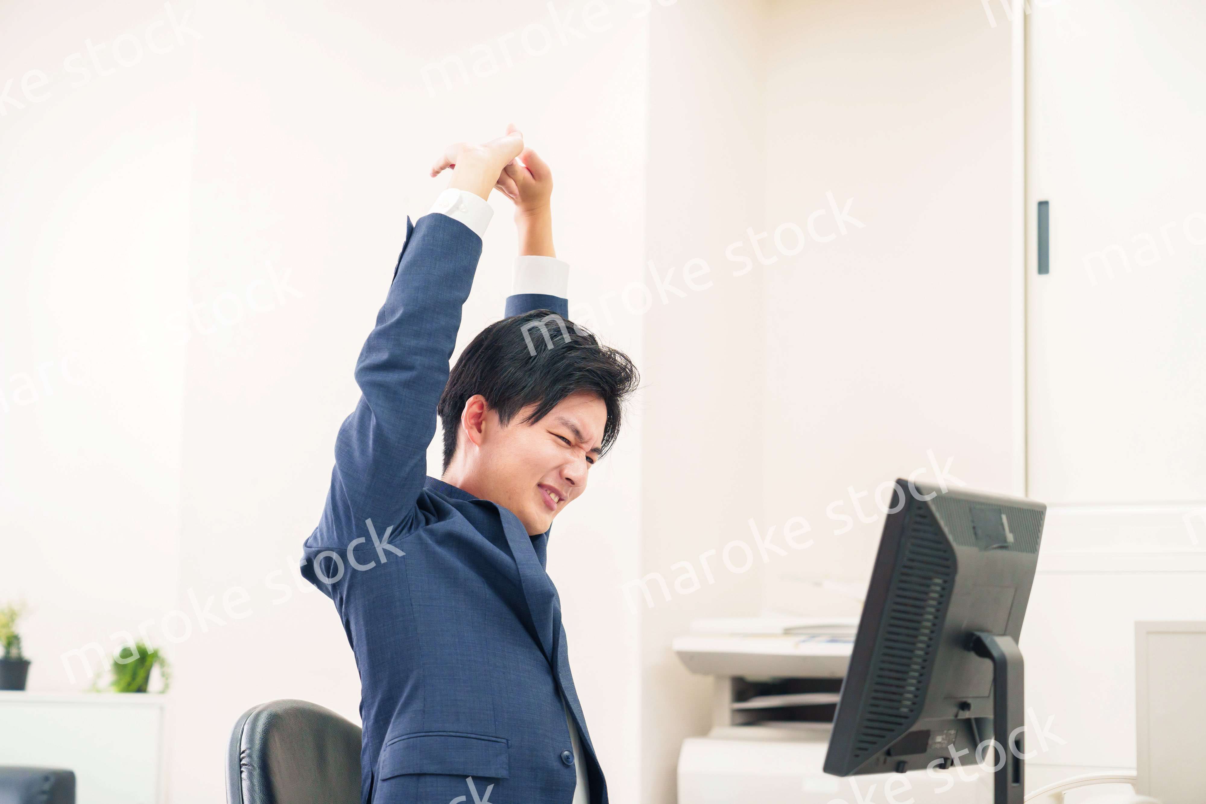 オフィスで肩こりに悩むビジネスマン