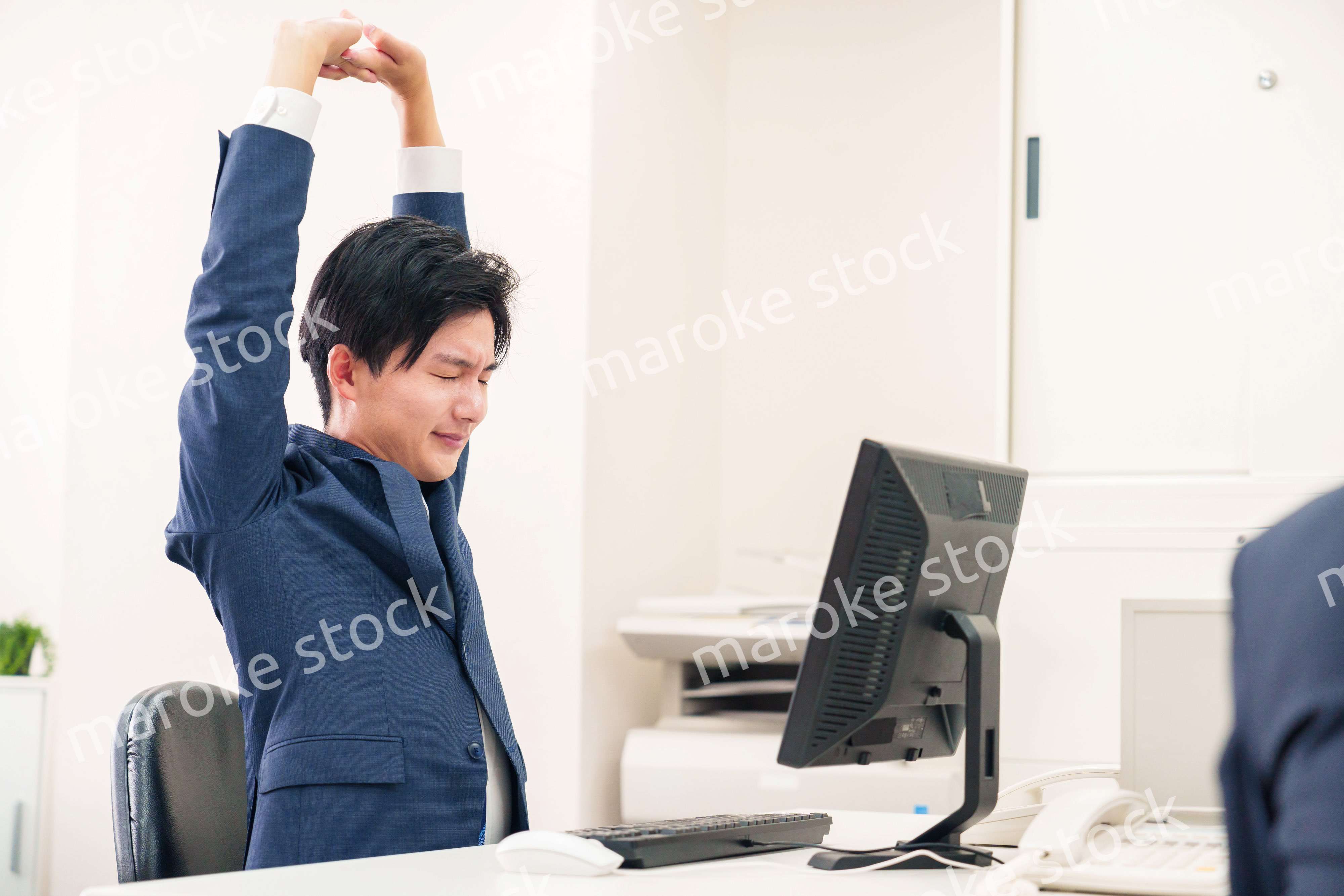 オフィスで肩こりに悩むビジネスマン