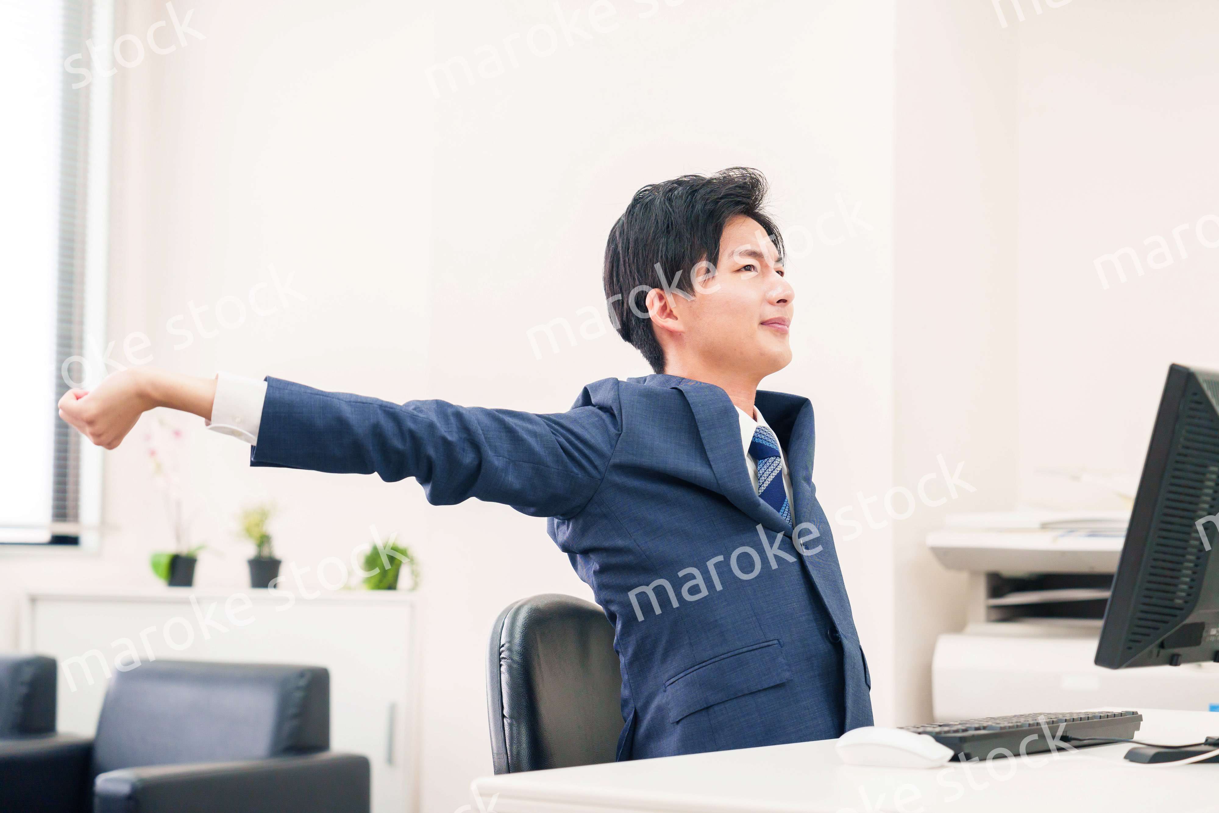 オフィスで肩こりに悩むビジネスマン