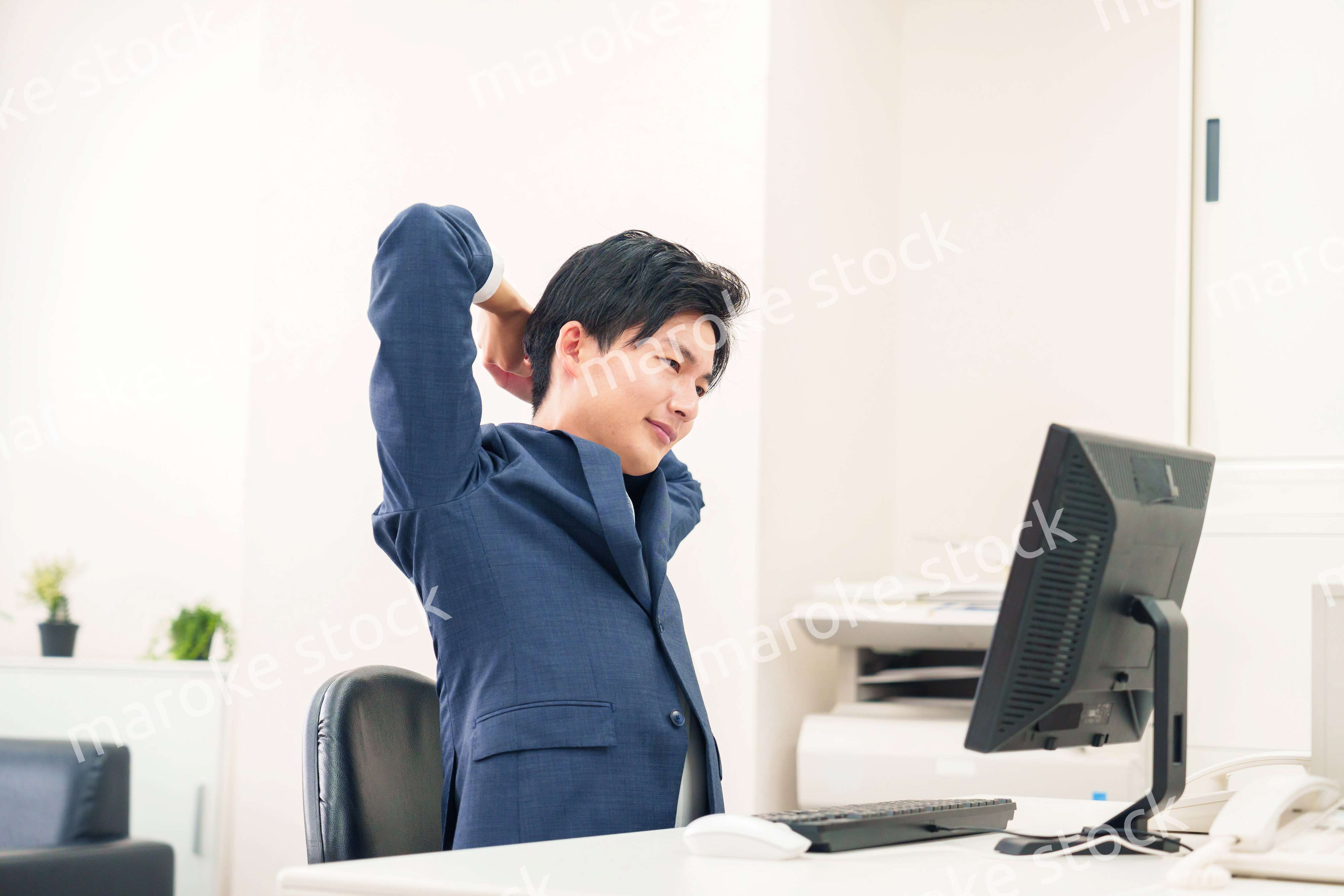オフィスで肩こりに悩むビジネスマン