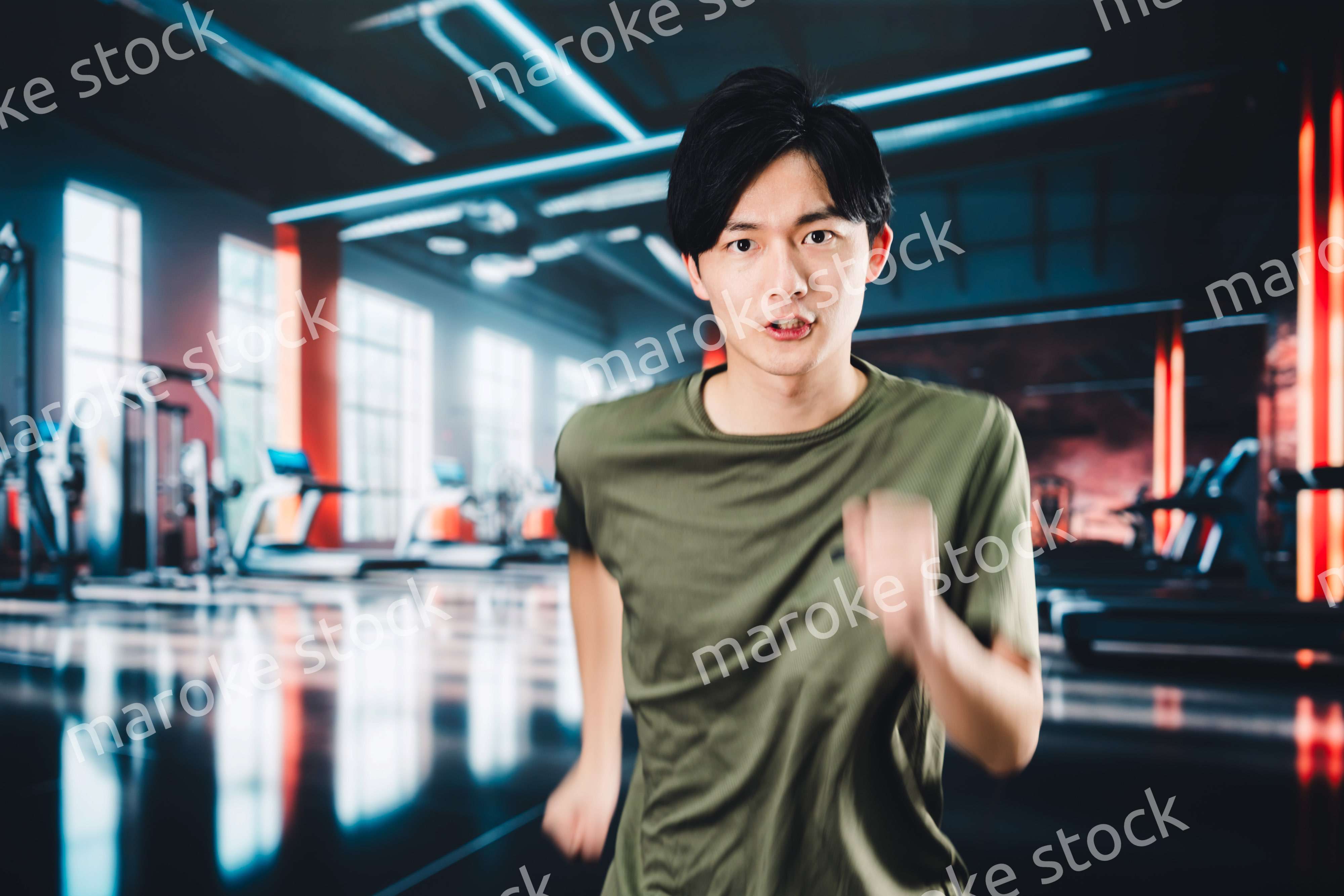 スポーツジムでランニングをする若い男性