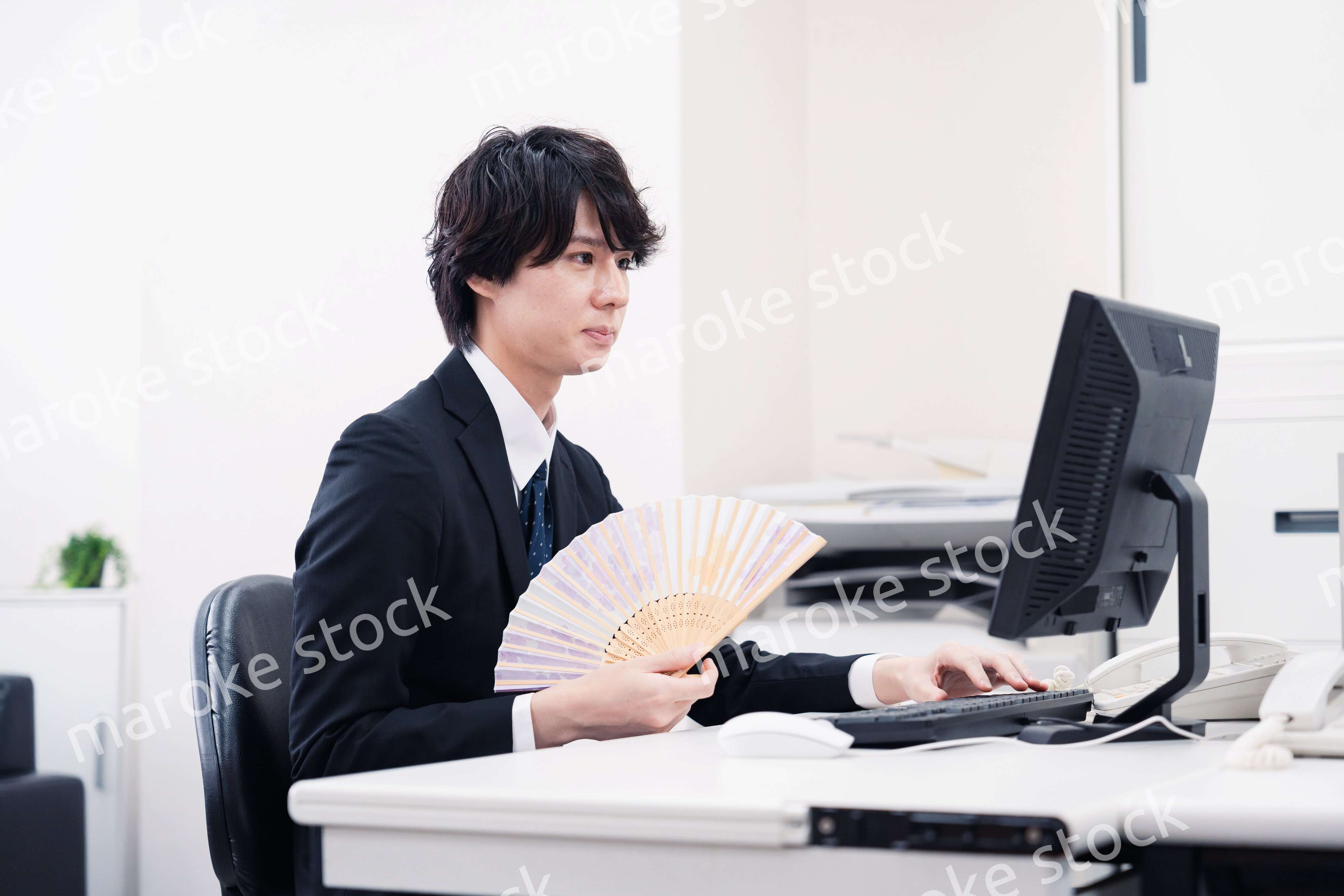 扇子で扇ぎながら仕事をするビジネスマン