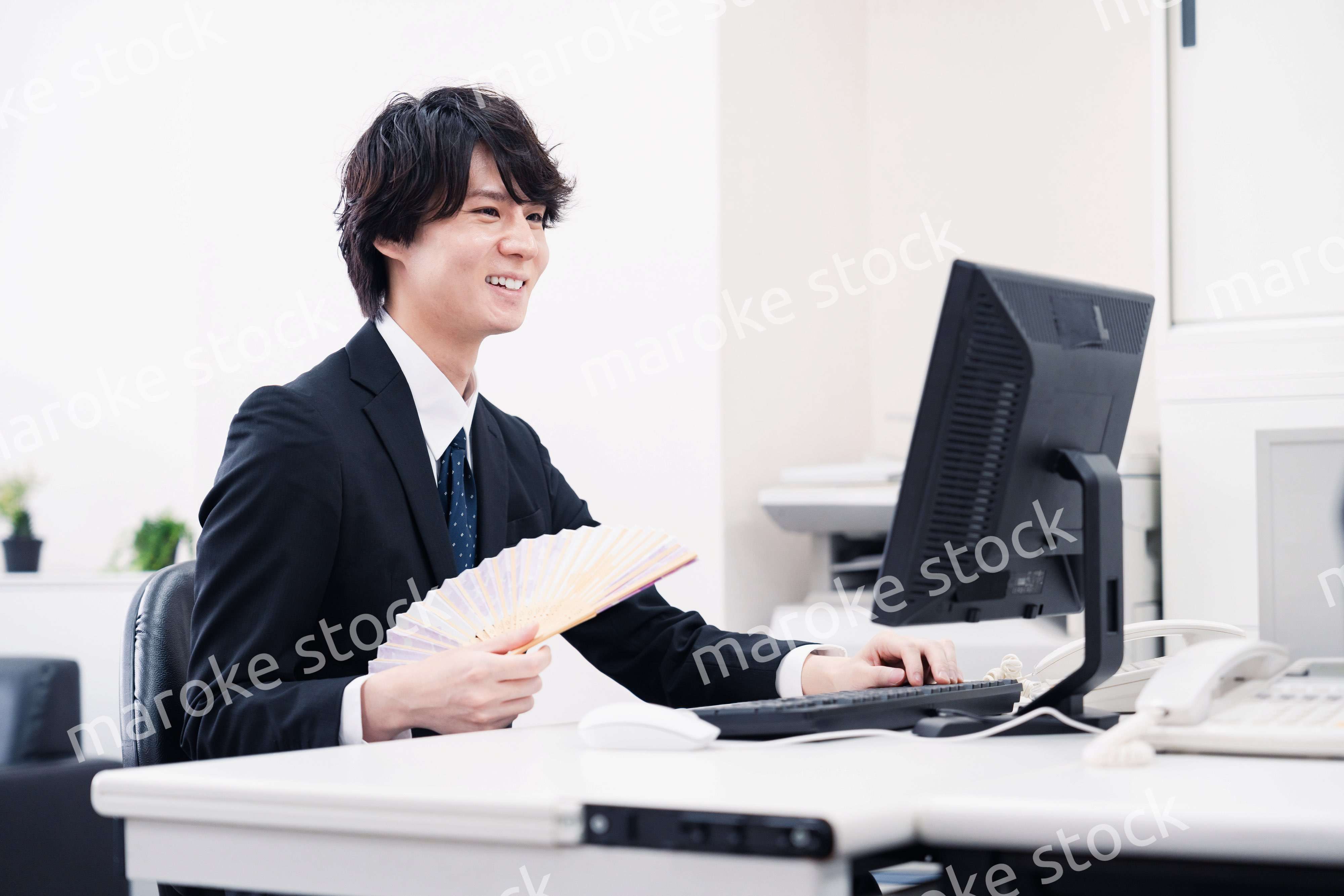 扇子で扇ぎながら仕事をするビジネスマン