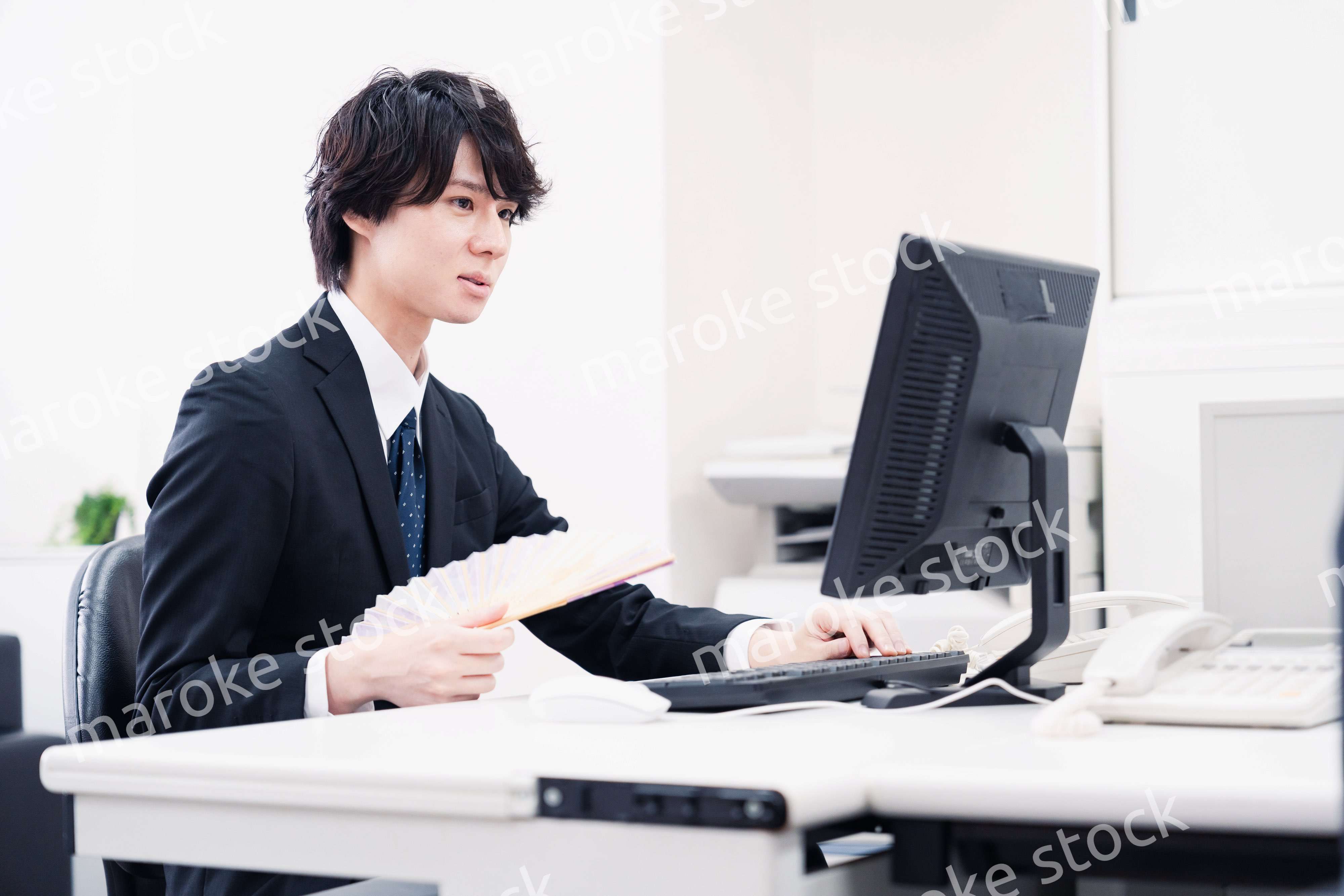 扇子で扇ぎながら仕事をするビジネスマン