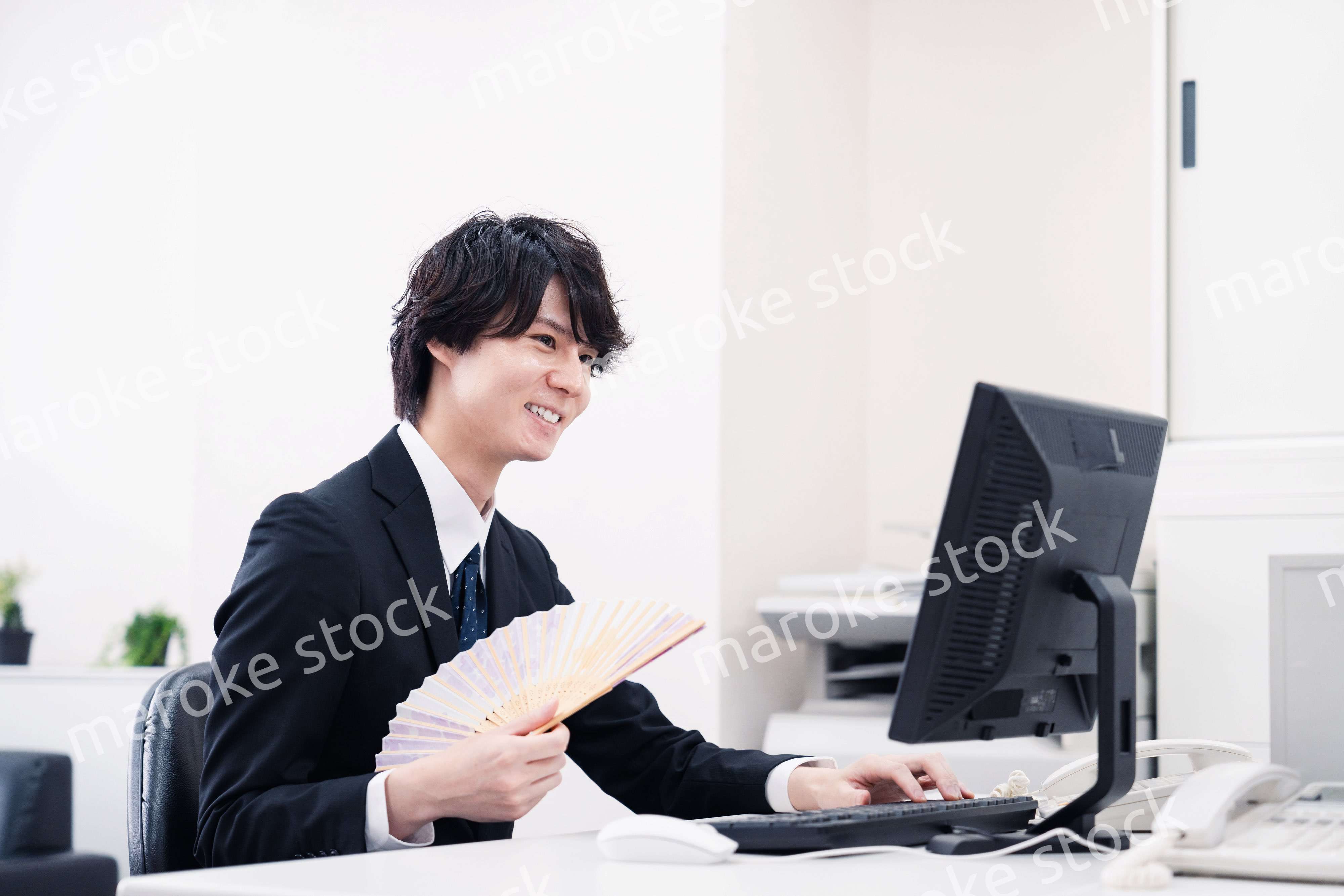 扇子で扇ぎながら仕事をするビジネスマン