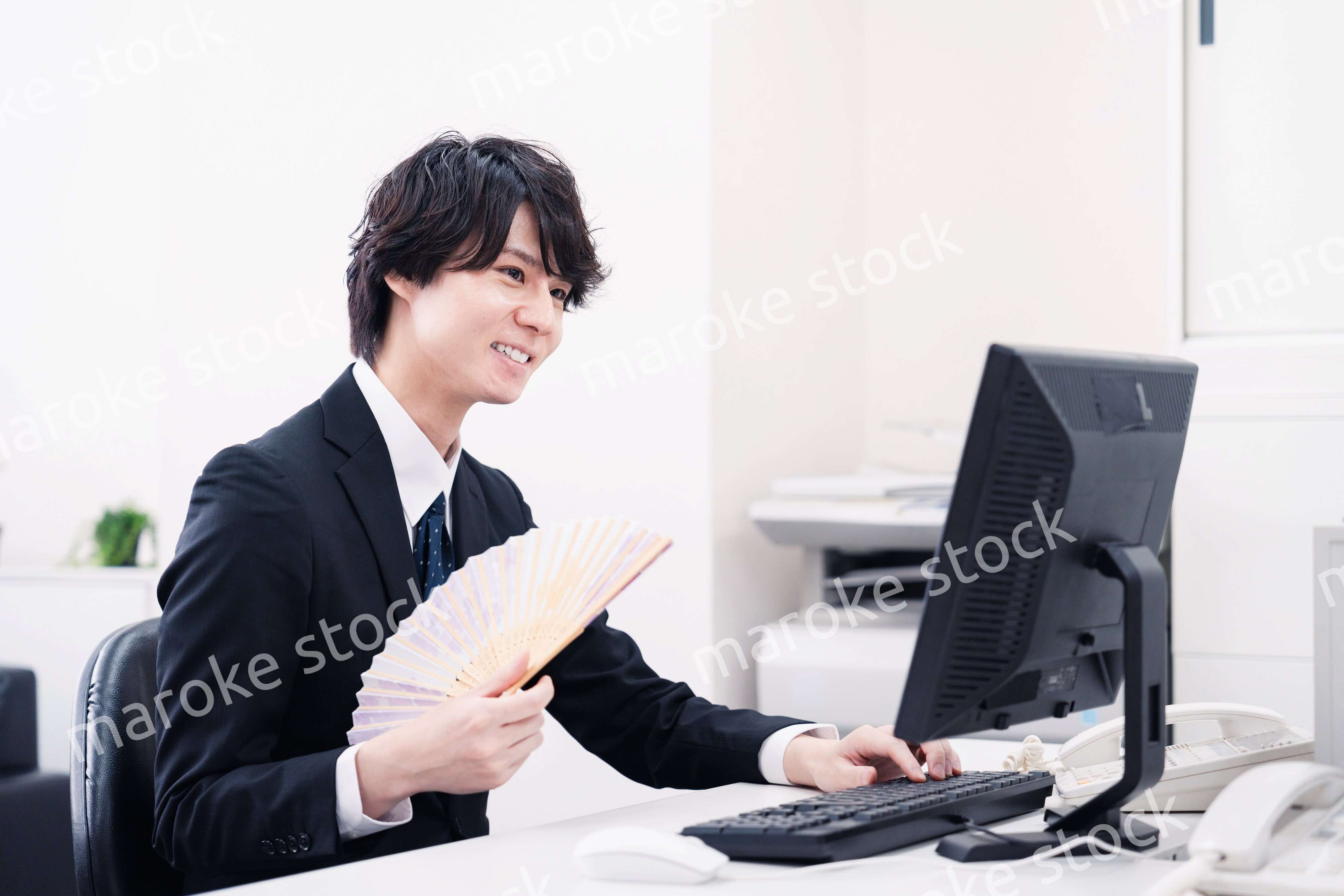 扇子で扇ぎながら仕事をするビジネスマン