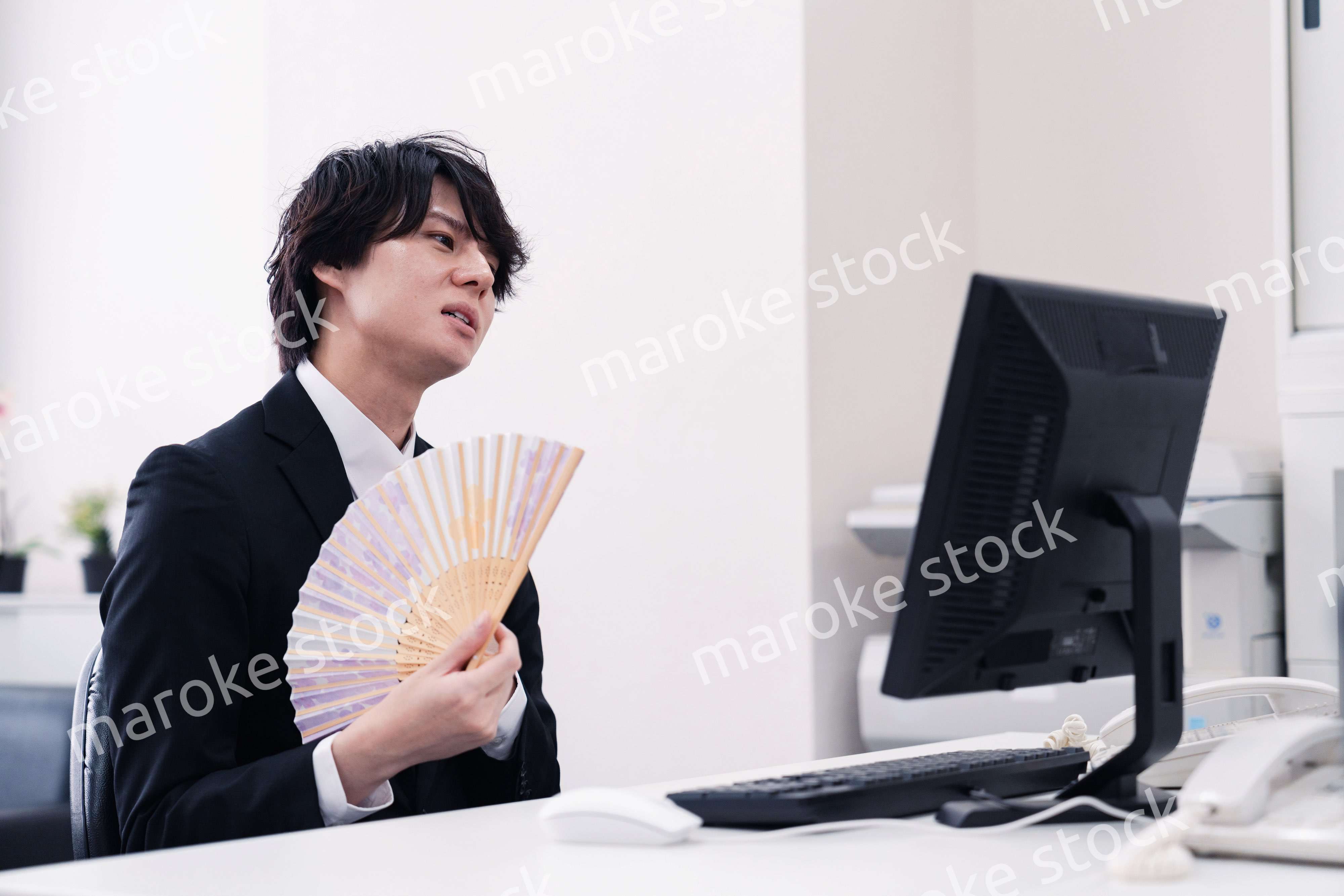 扇子で扇ぎながら仕事をするビジネスマン