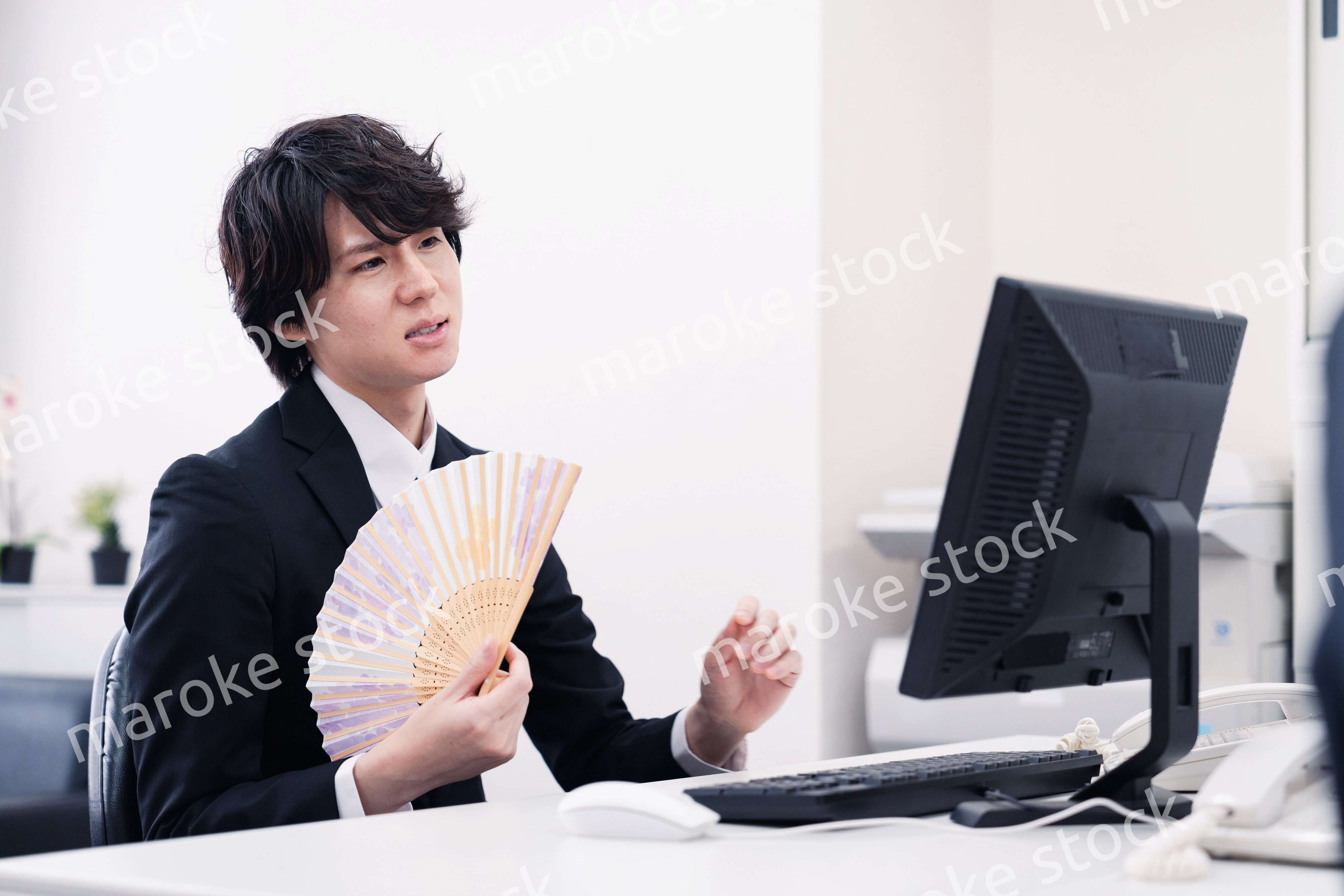 扇子で扇ぎながら仕事をするビジネスマン