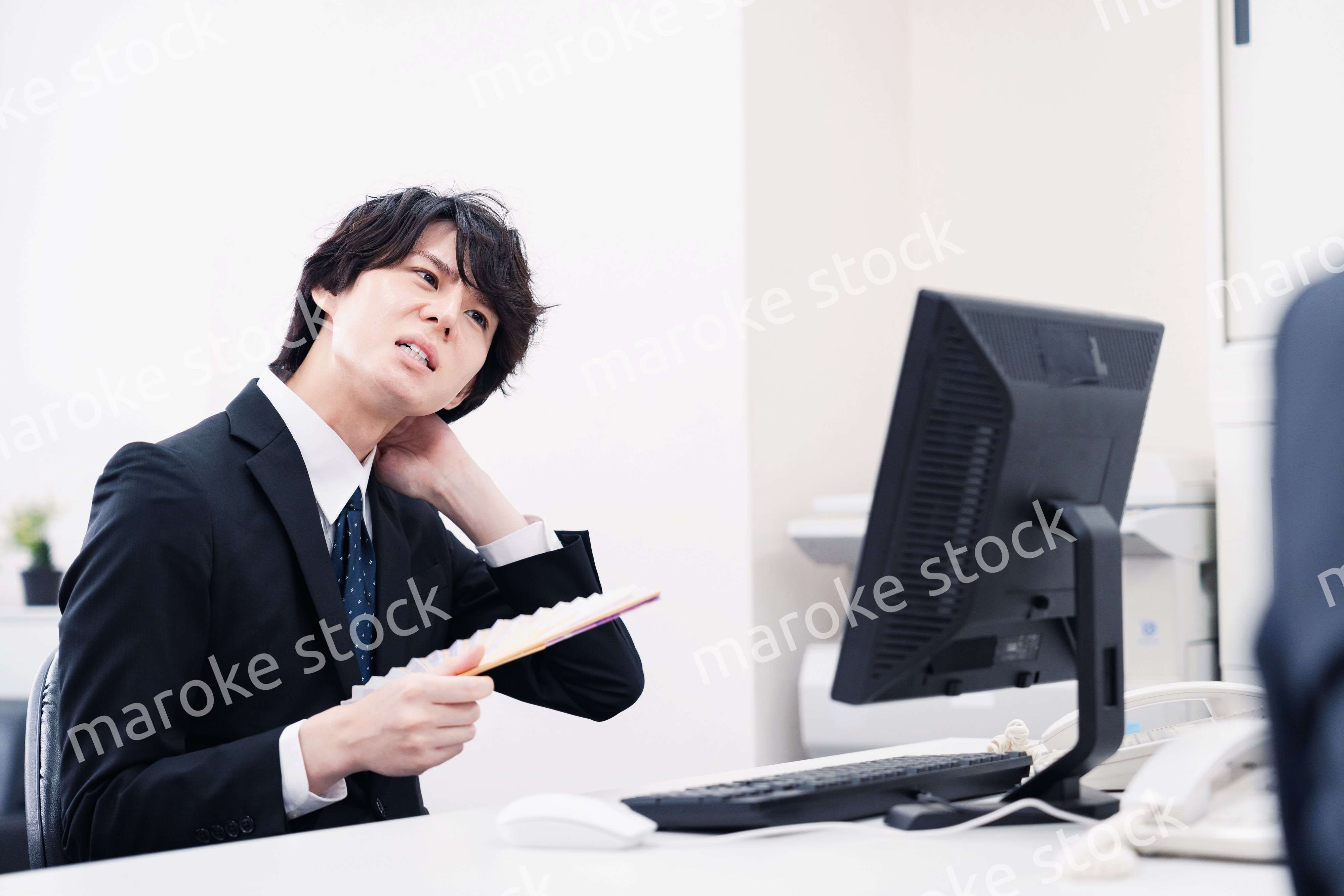 扇子で扇ぎながら仕事をするビジネスマン