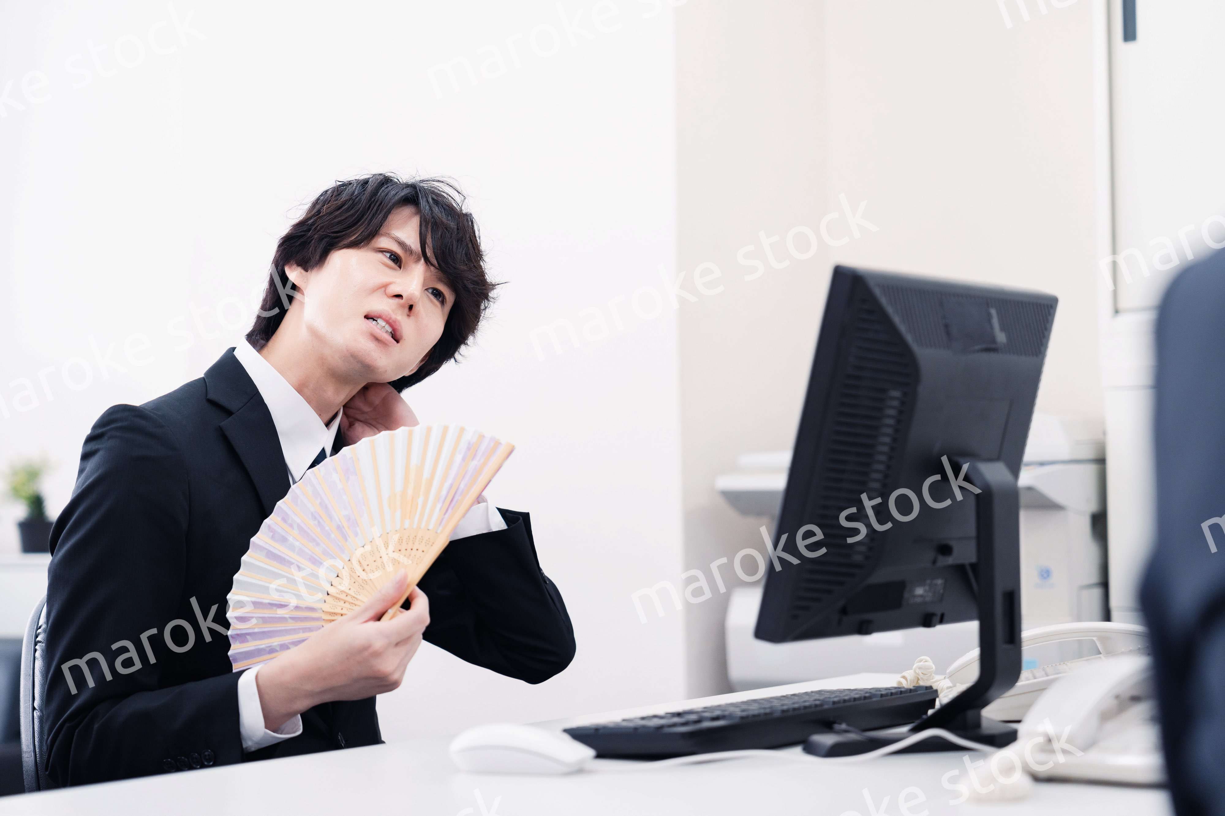 扇子で扇ぎながら仕事をするビジネスマン