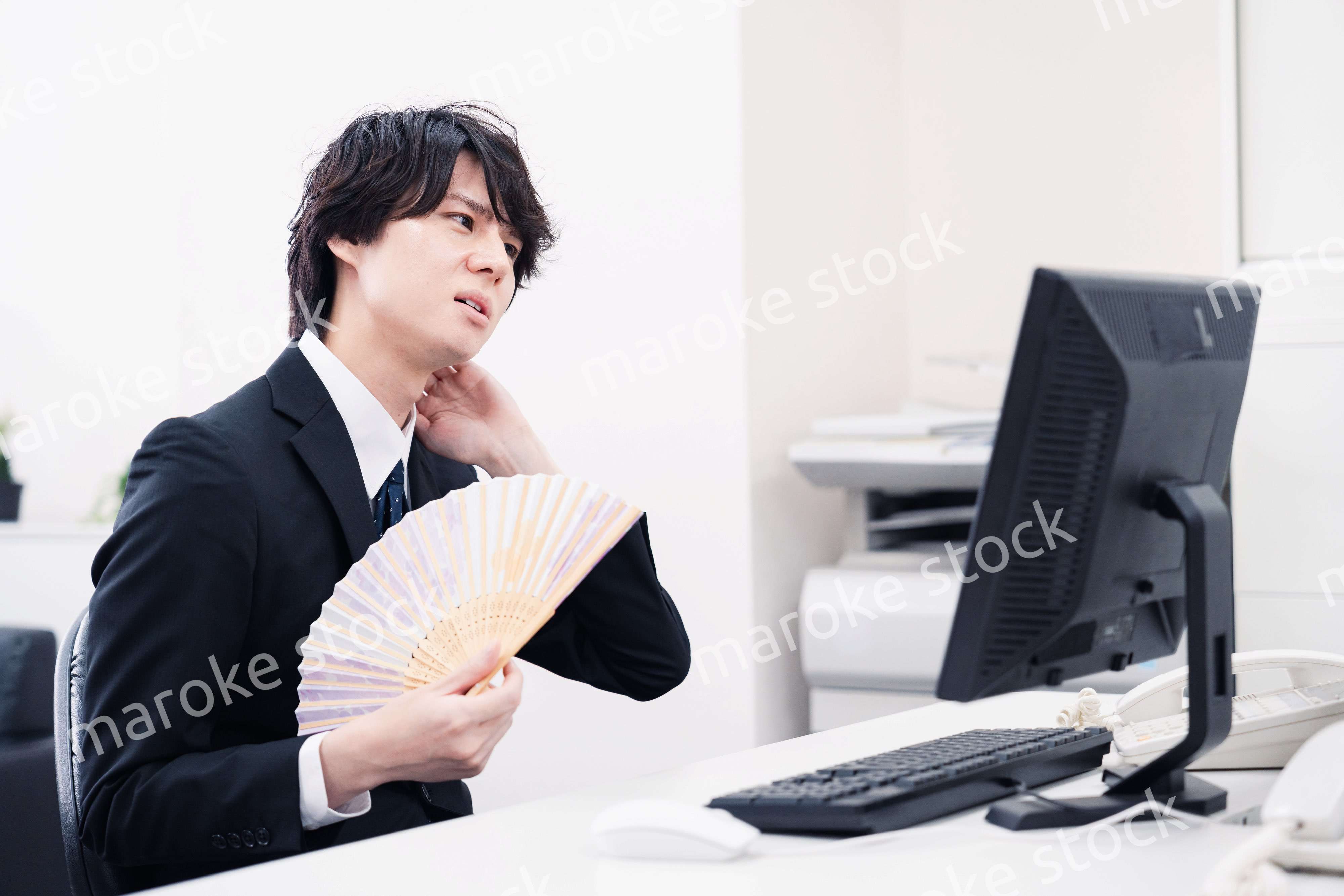 扇子で扇ぎながら仕事をするビジネスマン