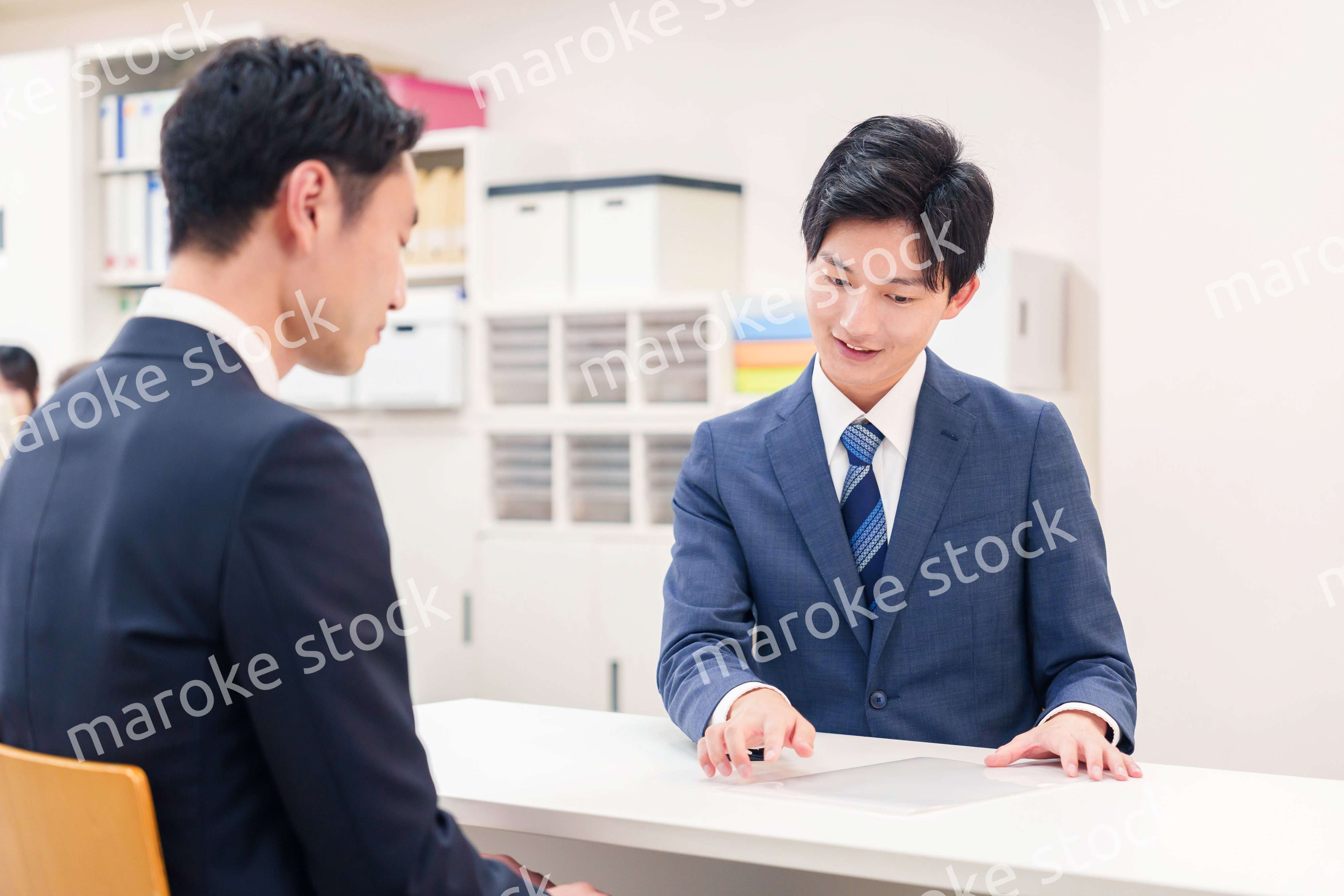 窓口で来客の対応をするビジネスマン