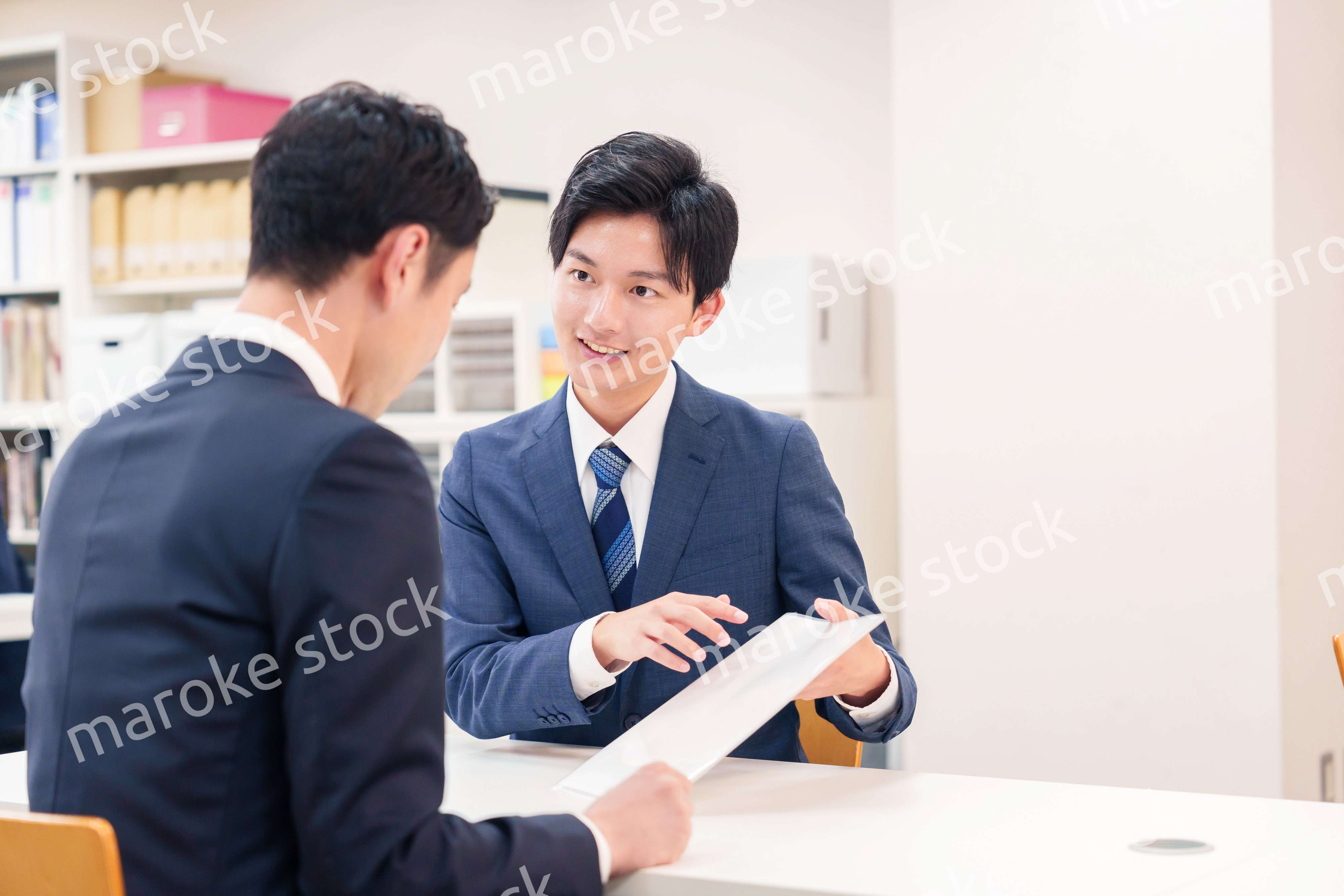 窓口で来客の対応をするビジネスマン