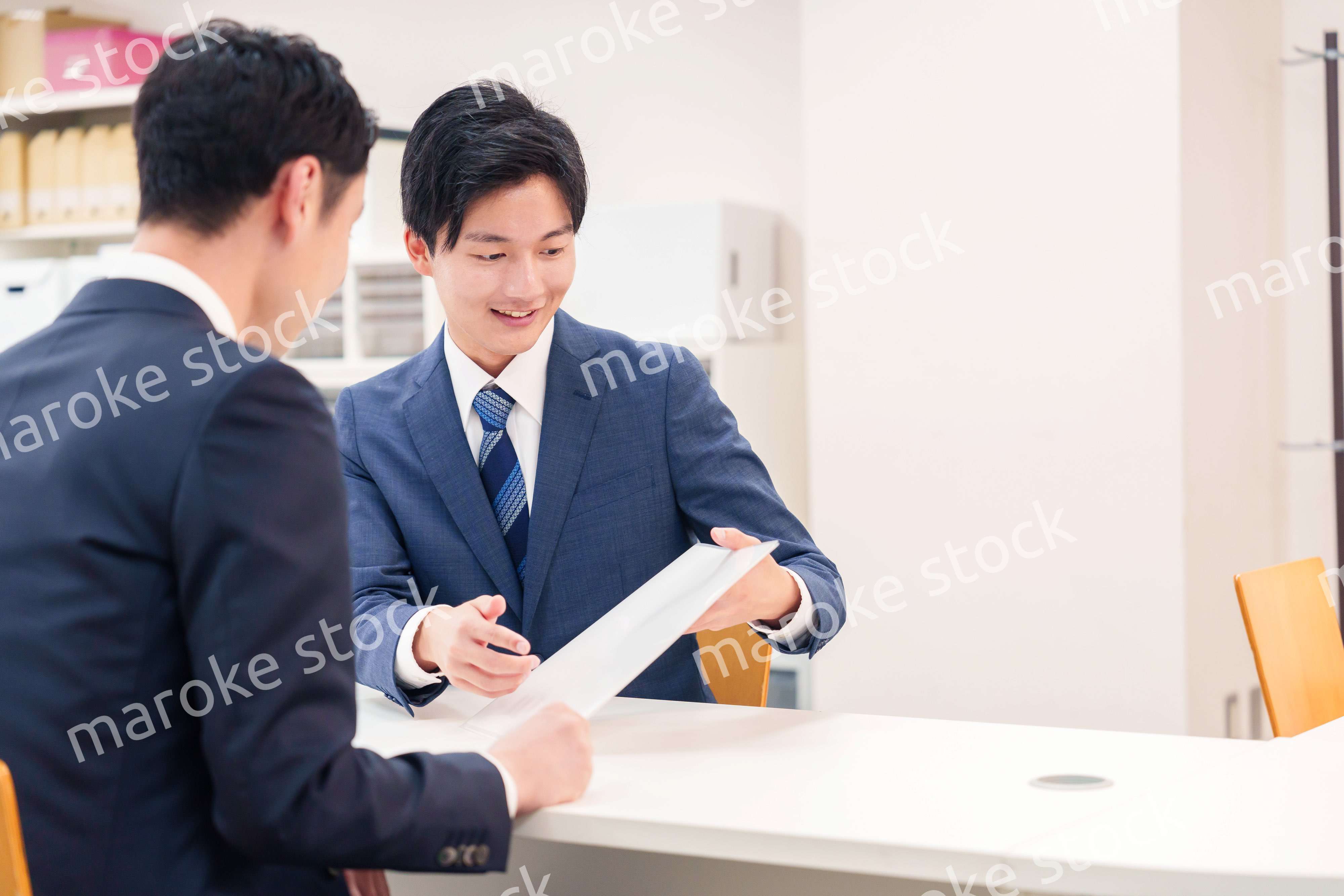 窓口で来客の対応をするビジネスマン