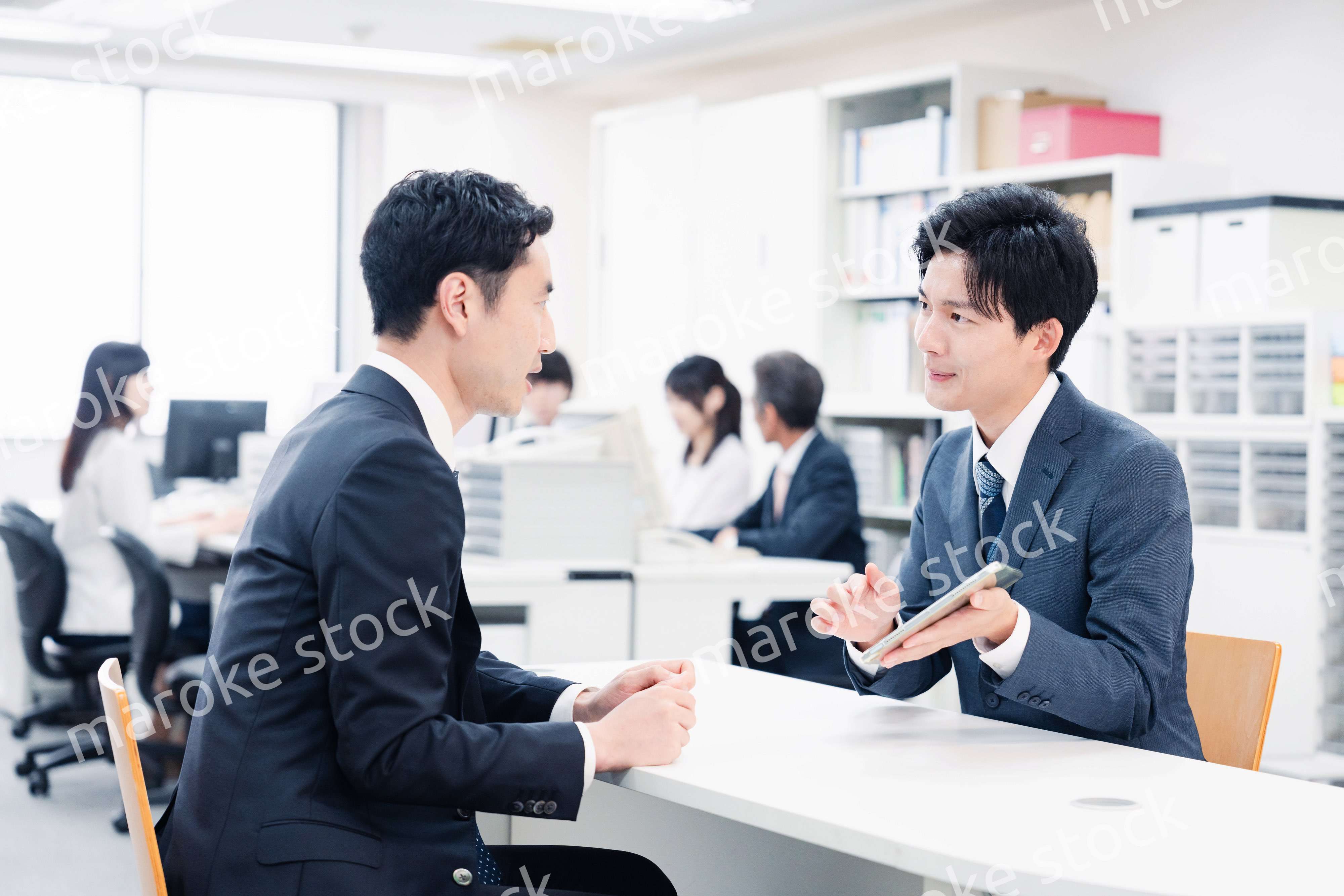 窓口でタブレットを用いて案内をする男性スタッフ