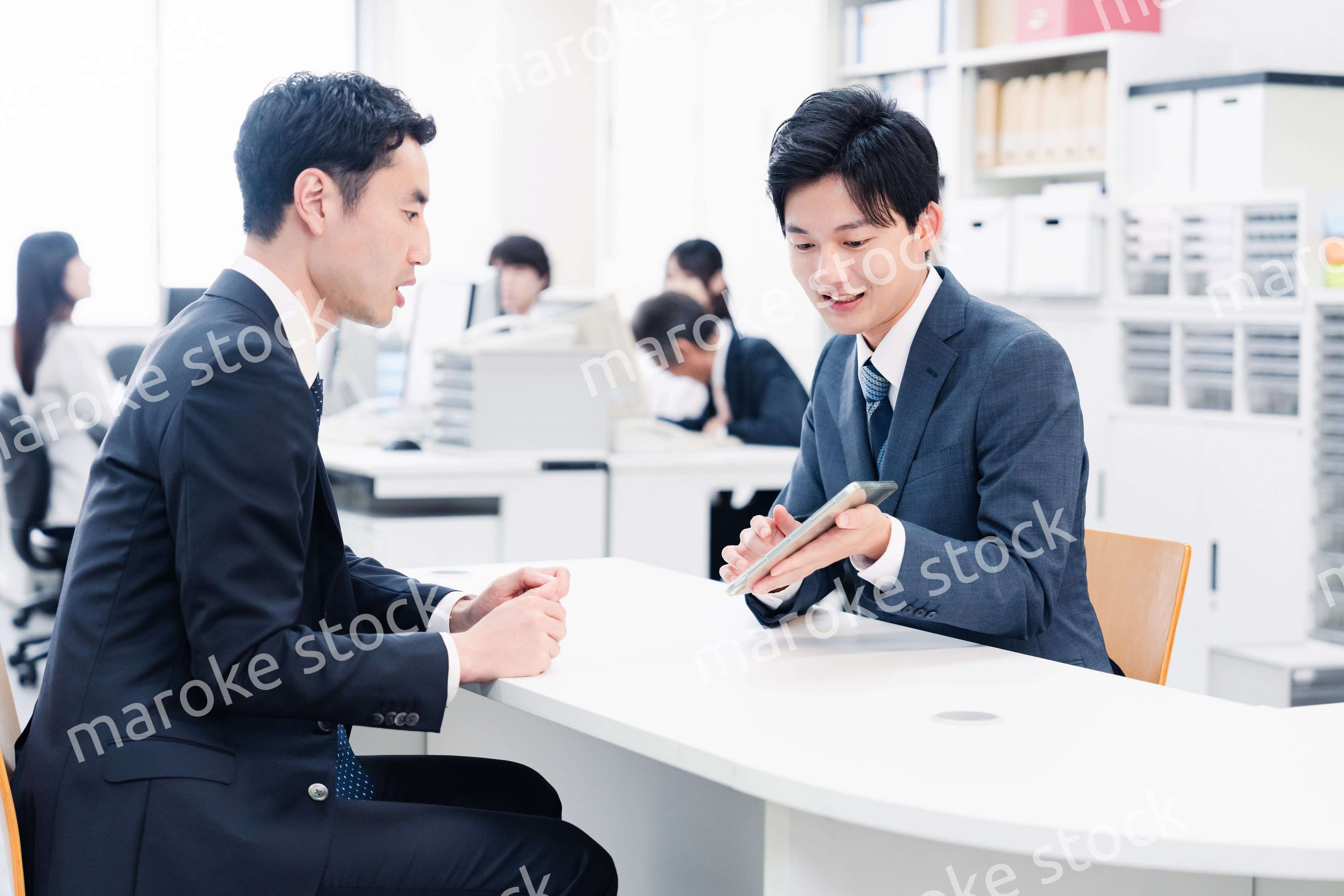 窓口でタブレットを用いて案内をする男性スタッフ