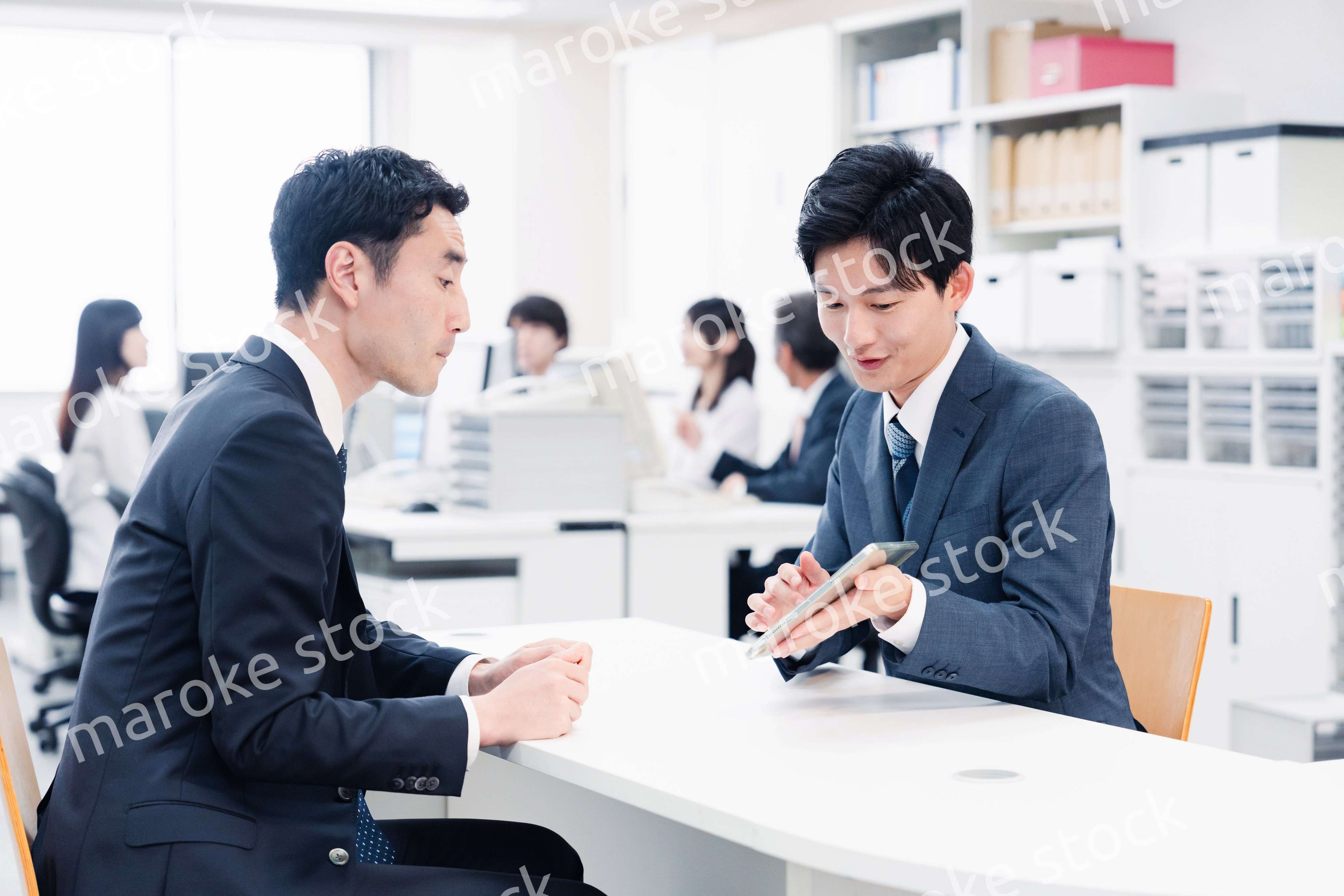 窓口でタブレットを用いて案内をする男性スタッフ