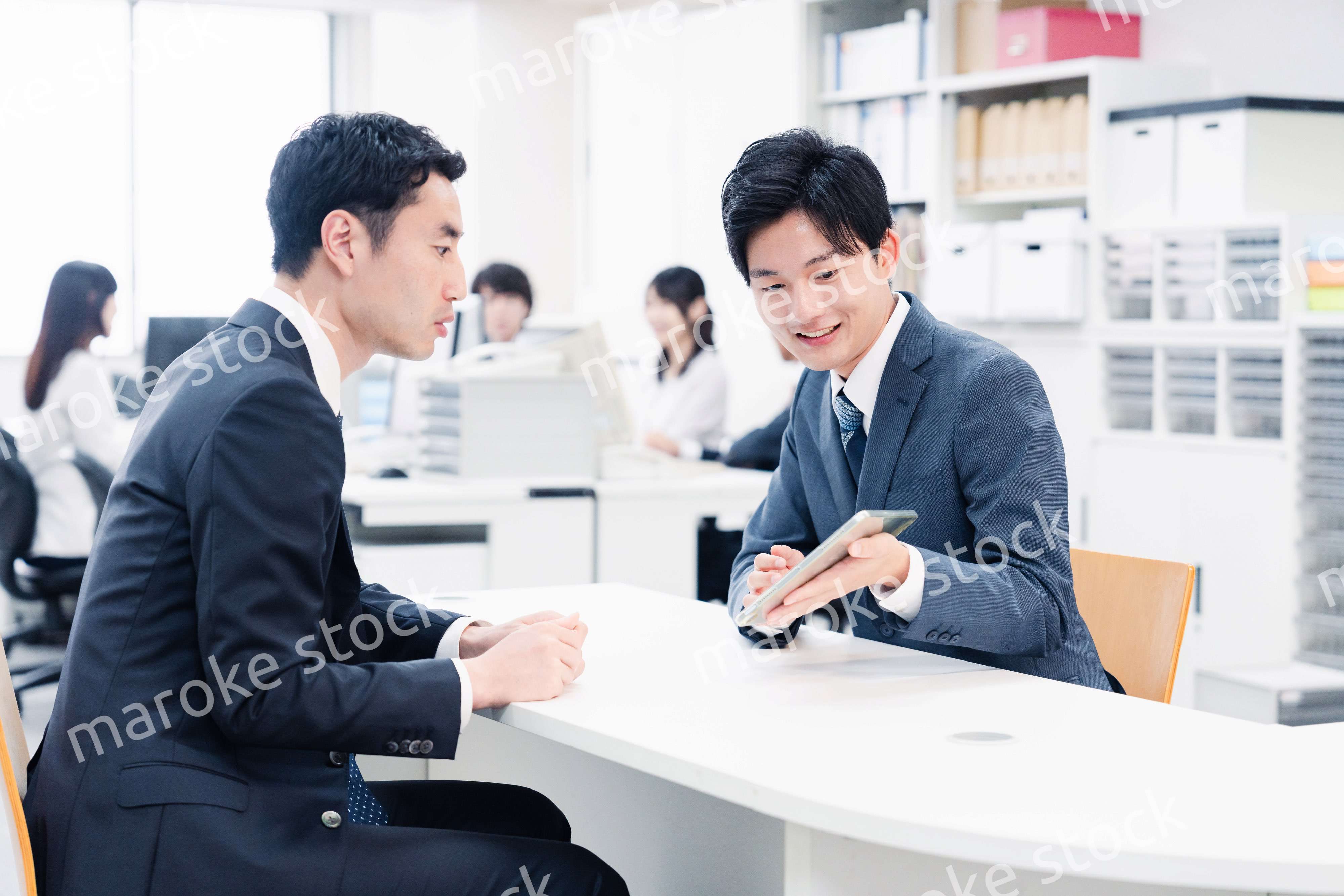 窓口でタブレットを用いて案内をする男性スタッフ