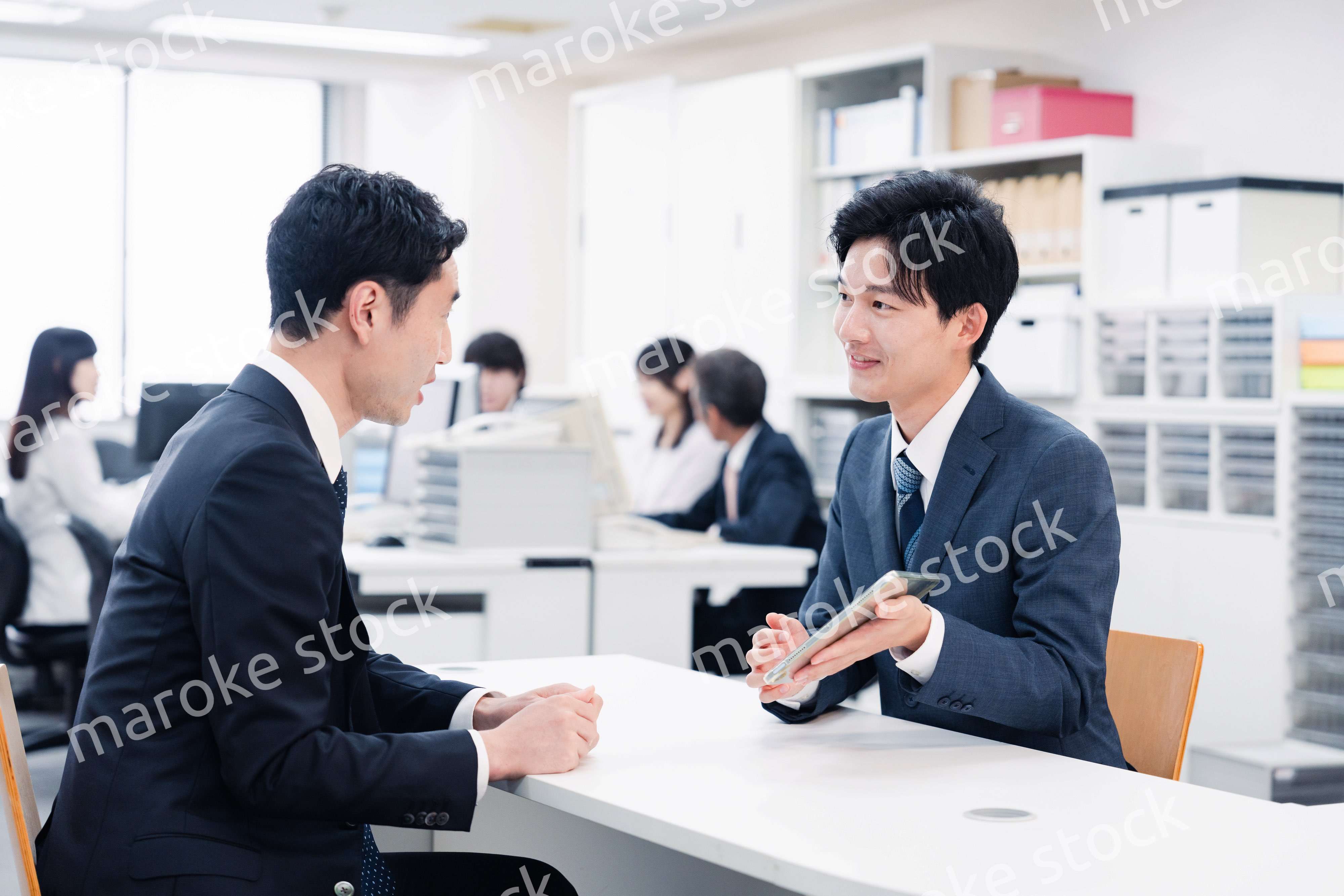 窓口でタブレットを用いて案内をする男性スタッフ