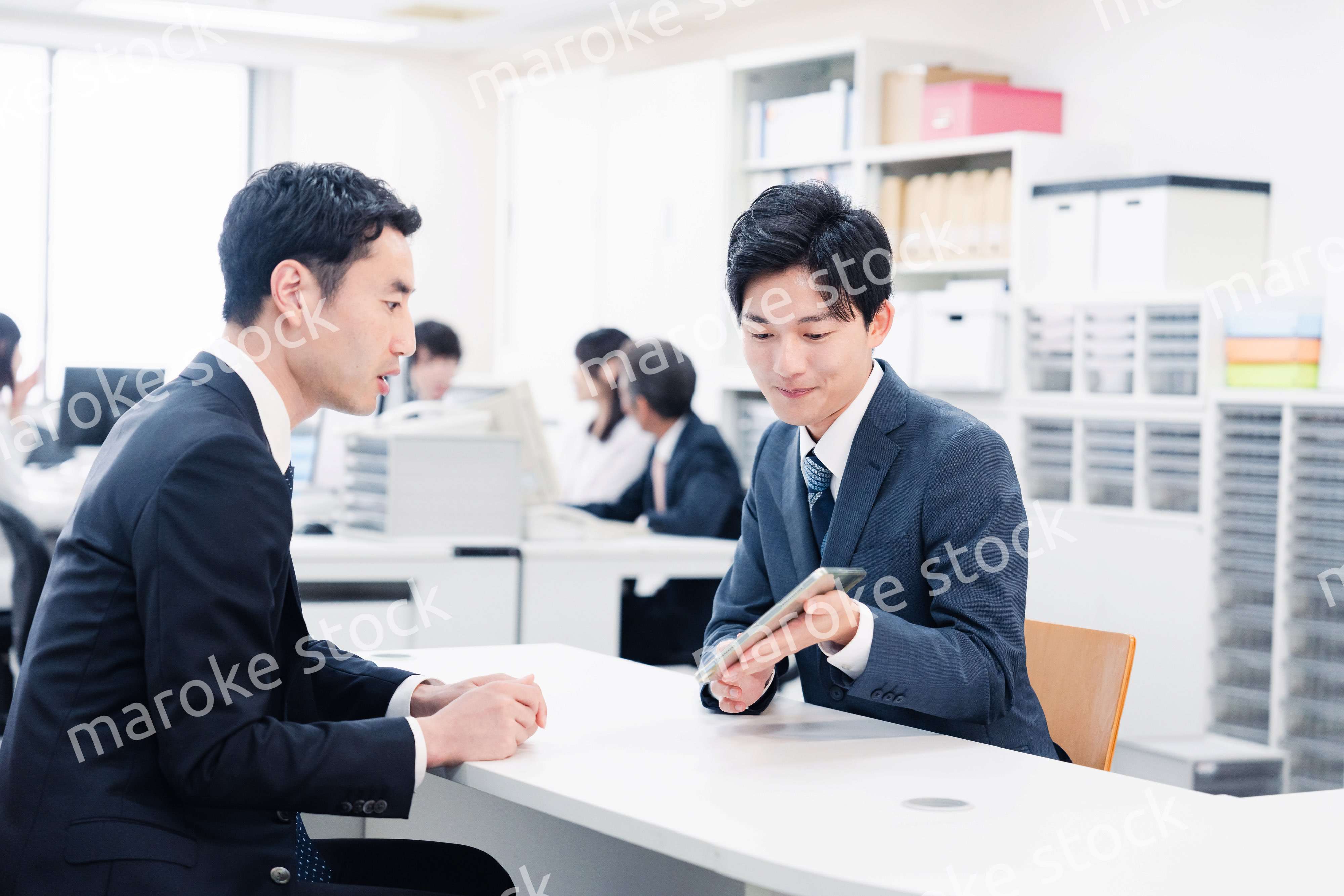 窓口でタブレットを用いて案内をする男性スタッフ