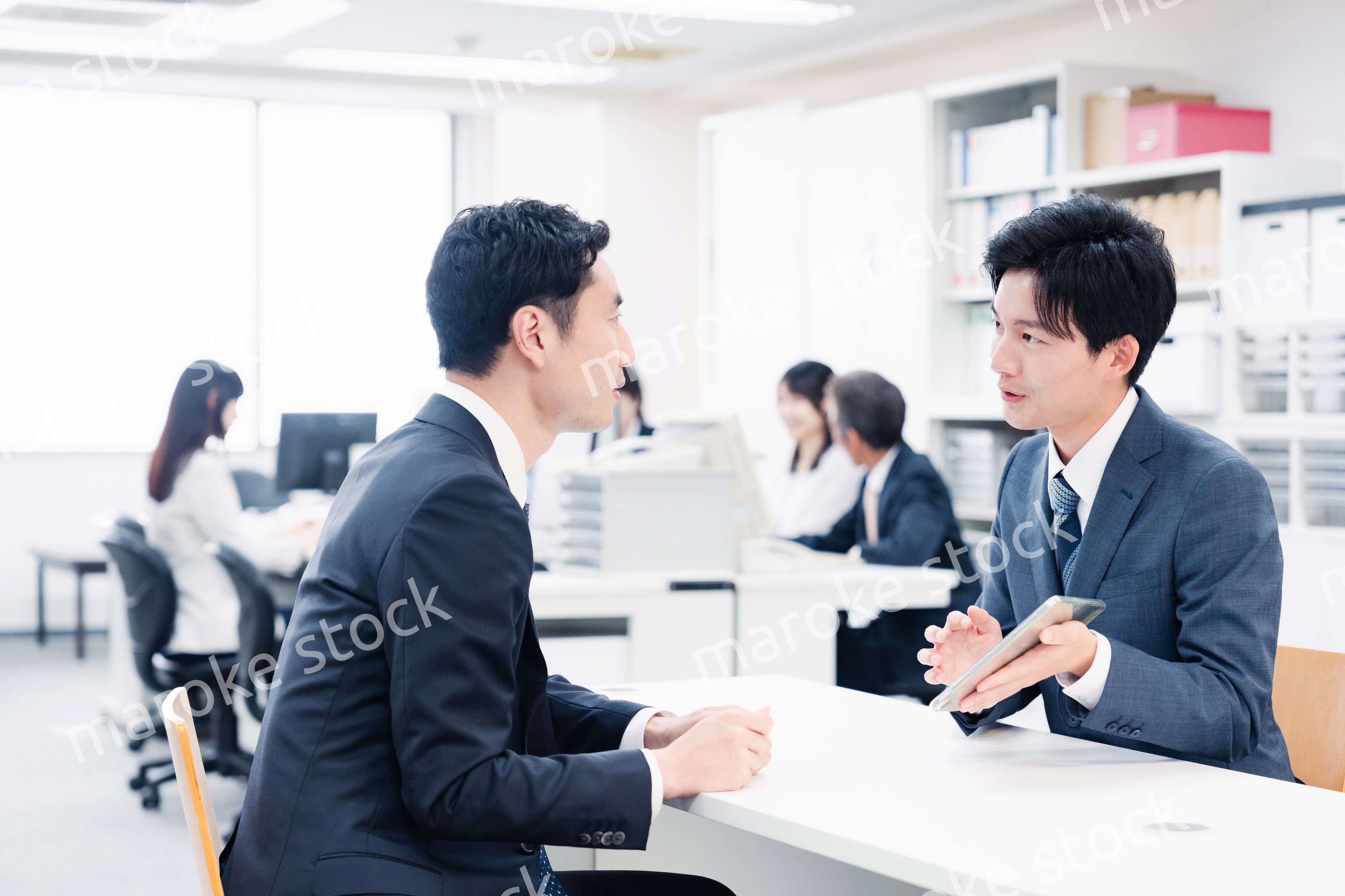 窓口でタブレットを用いて案内をする男性スタッフ