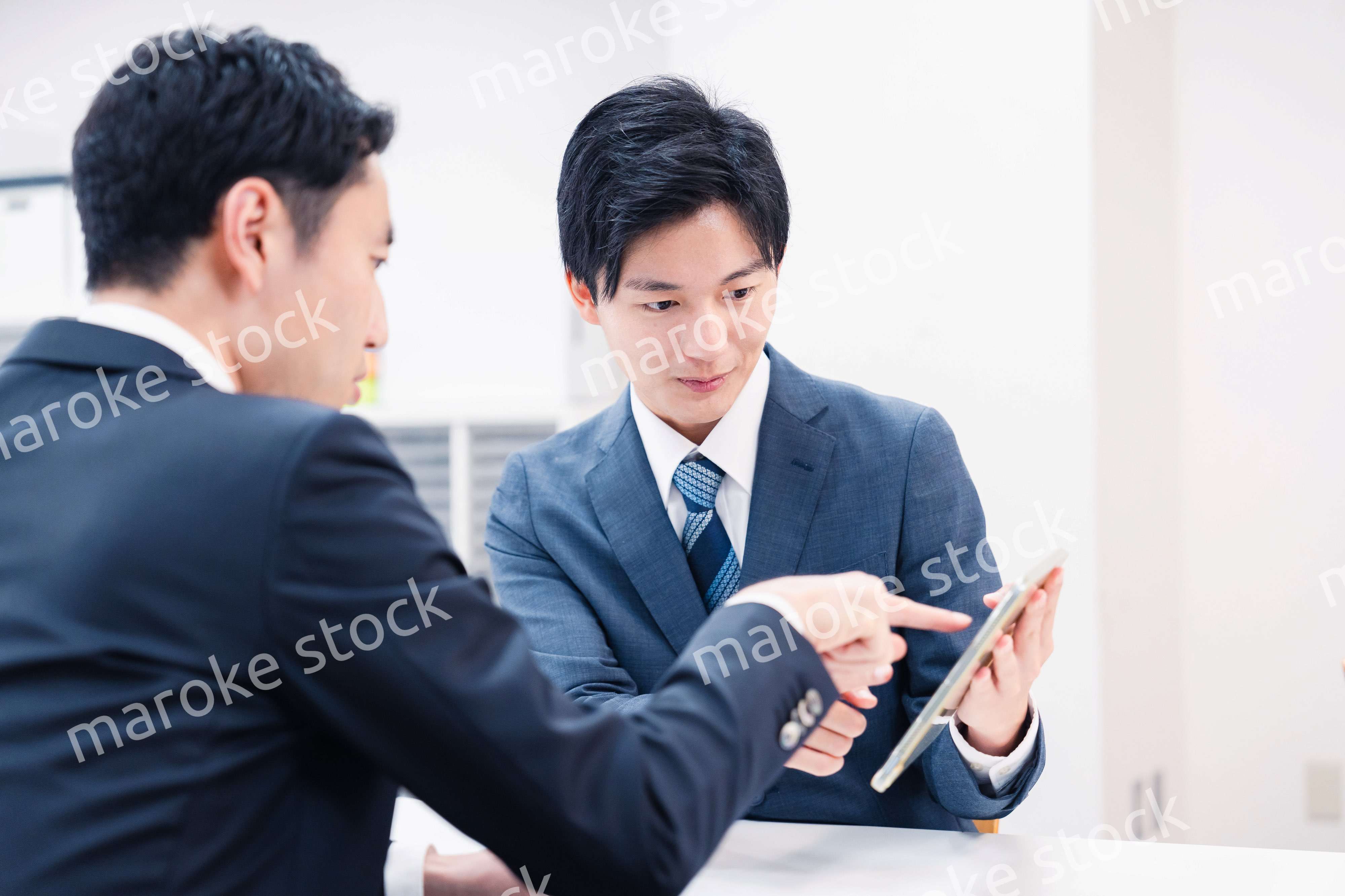 タブレット端末を使い窓口で説明をするビジネスマン