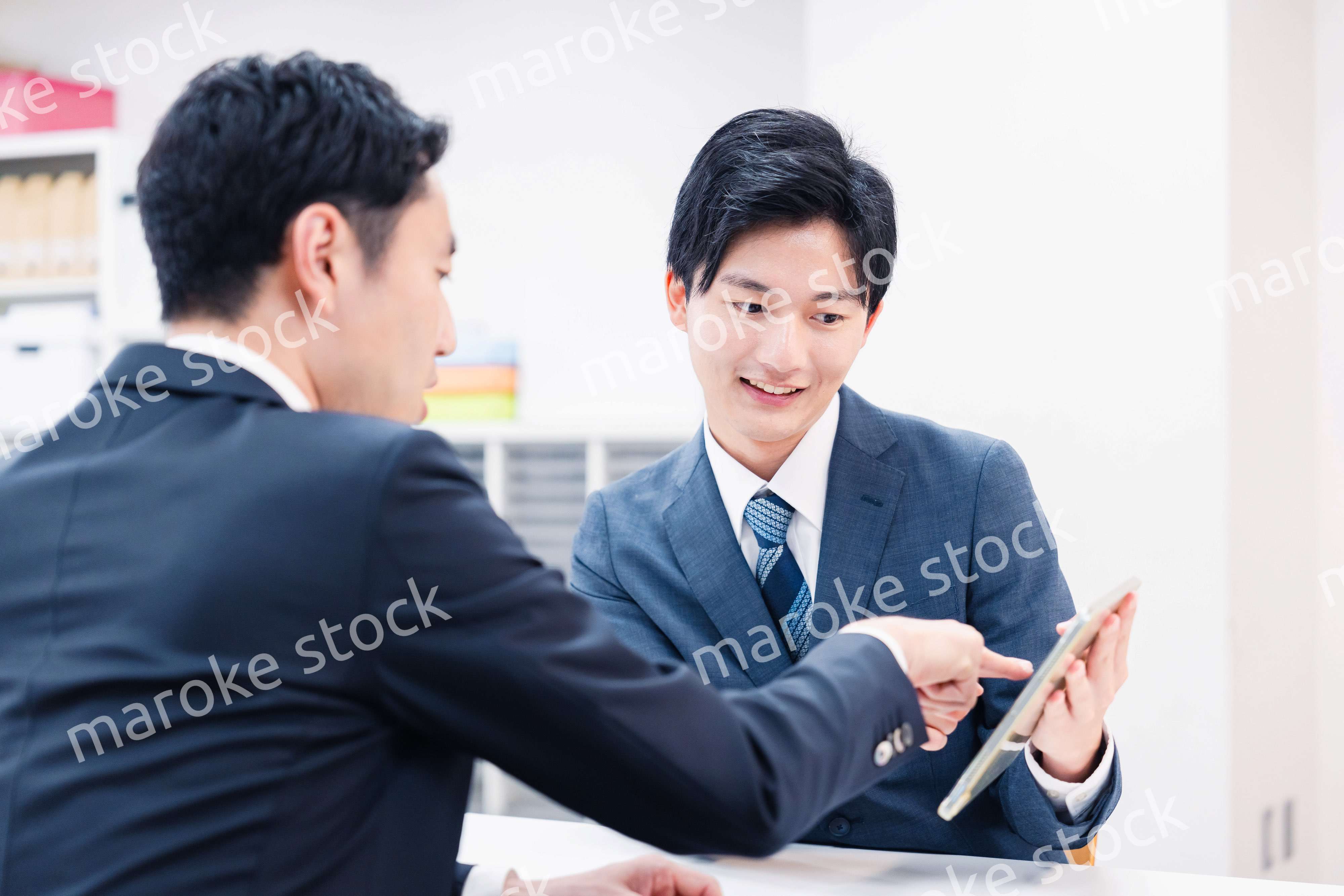 タブレット端末を使い窓口で説明をするビジネスマン