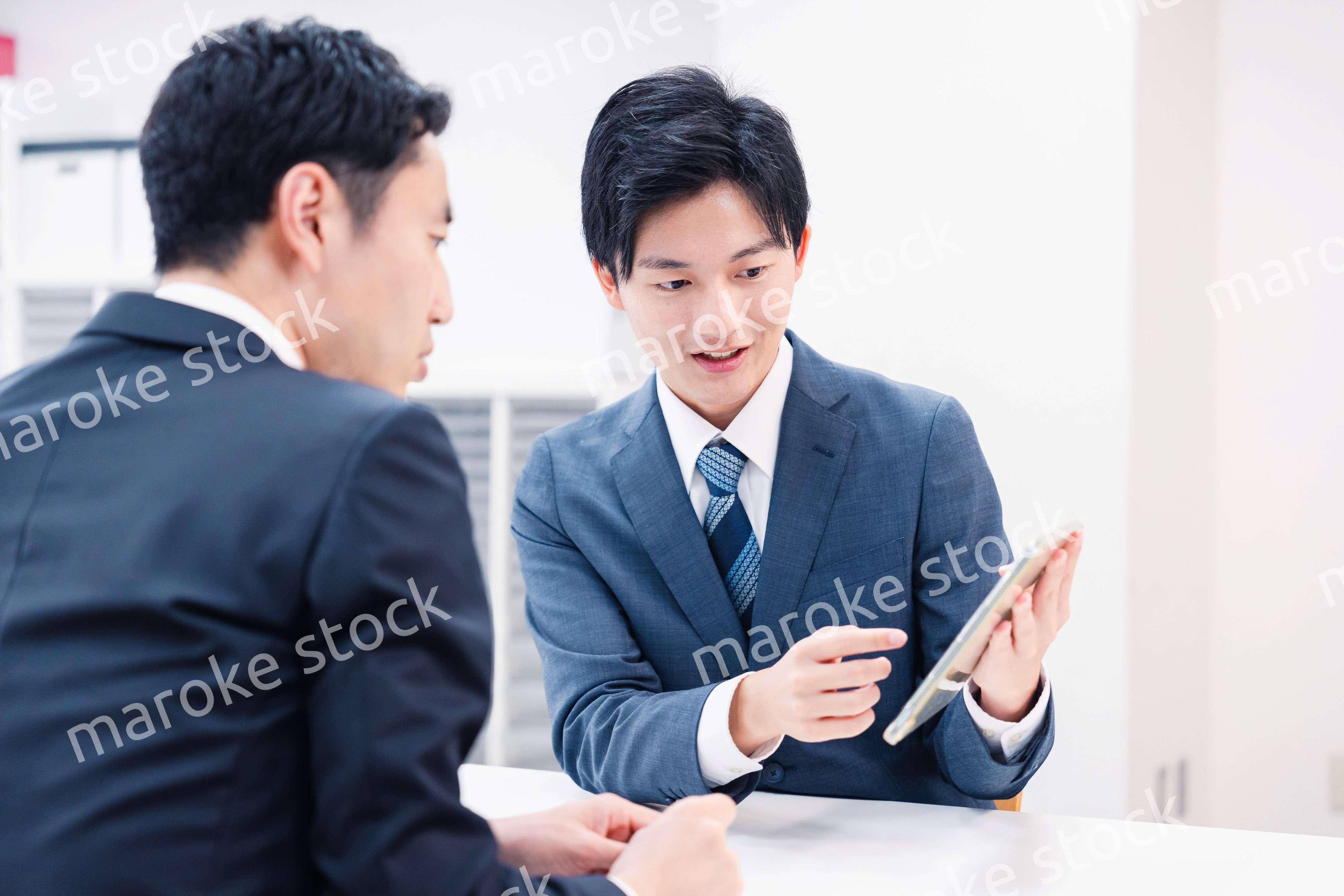 タブレット端末を使い窓口で説明をするビジネスマン