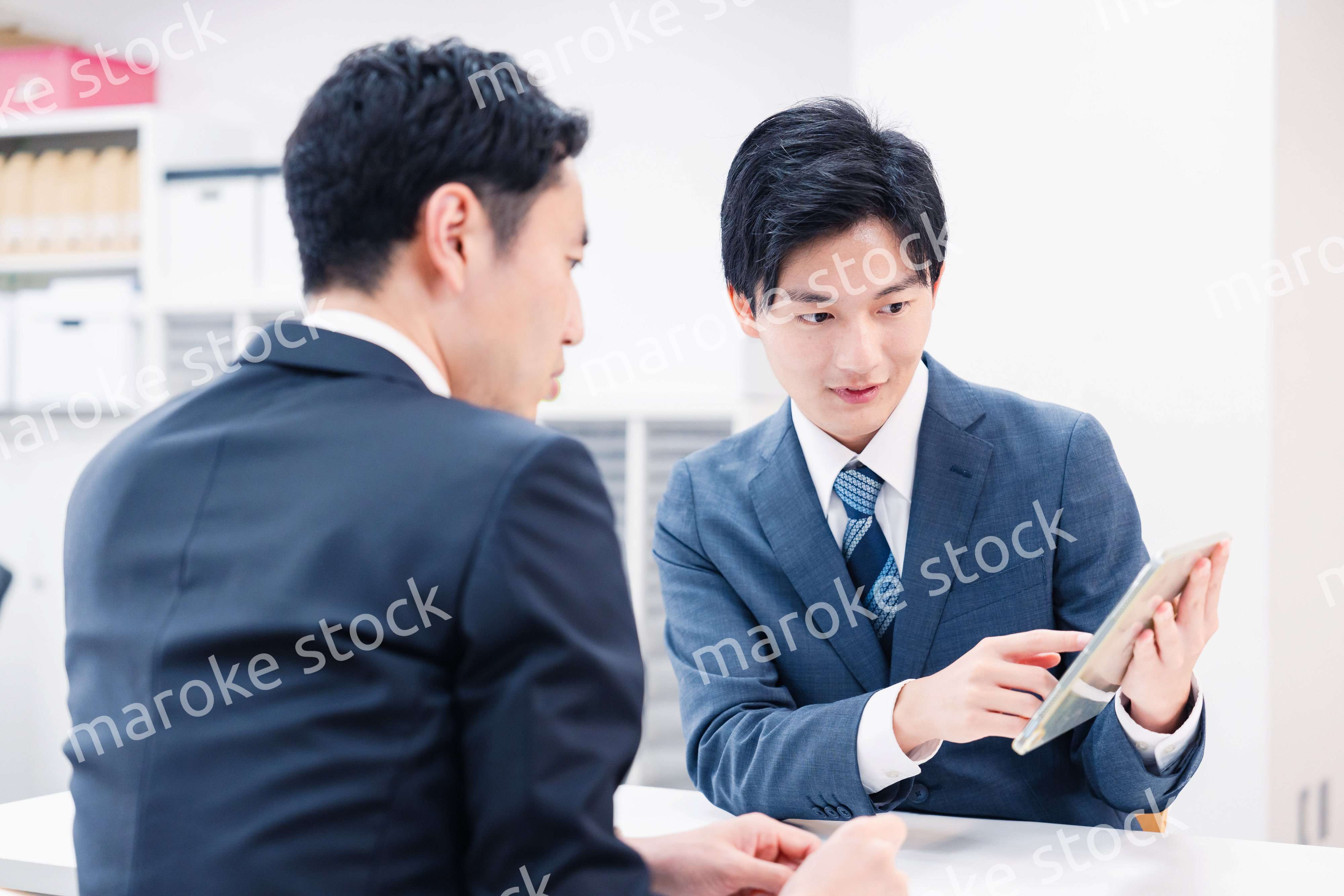 タブレット端末を使い窓口で説明をするビジネスマン