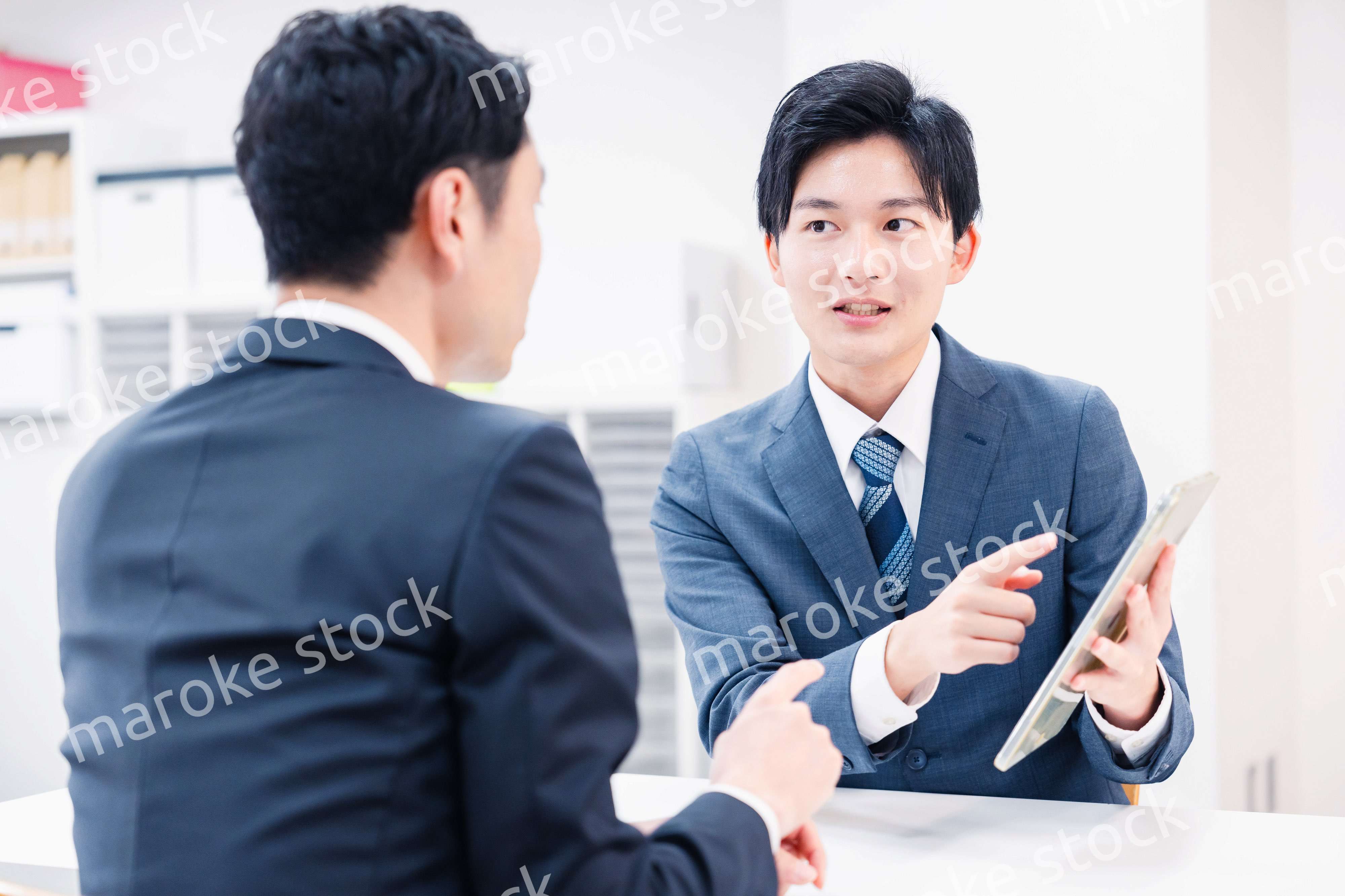 タブレット端末を使い窓口で説明をするビジネスマン