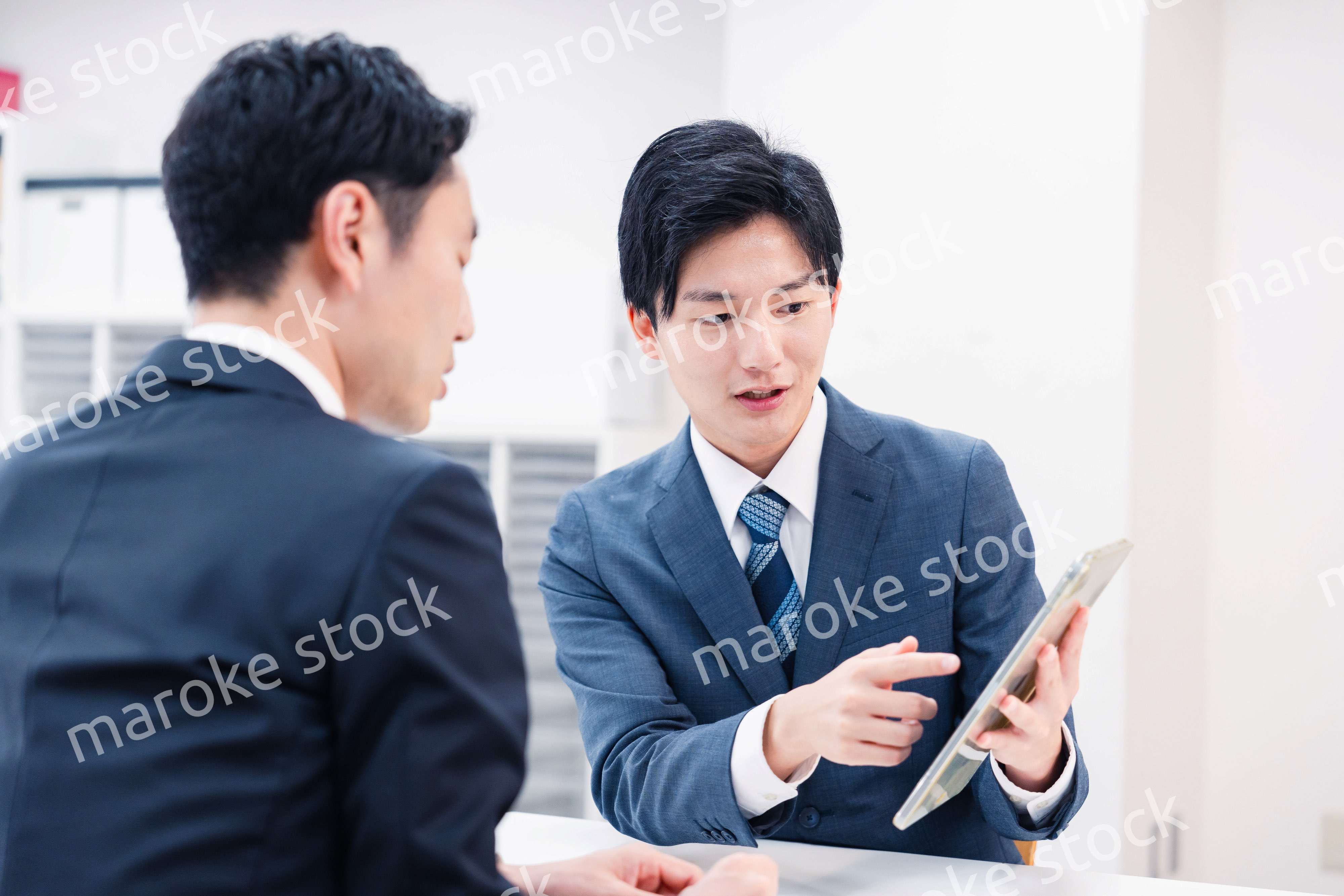 タブレット端末を使い窓口で説明をするビジネスマン