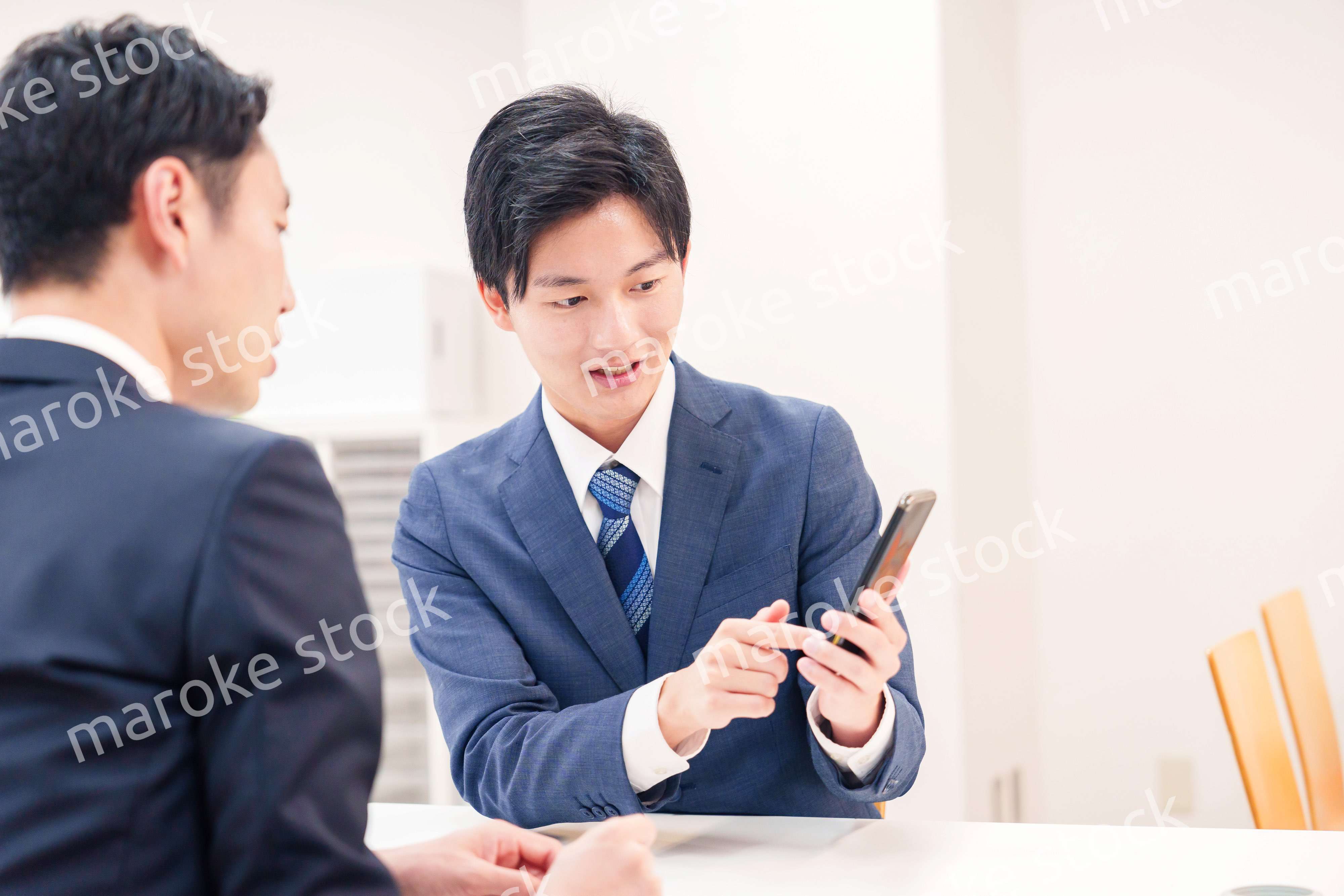 スマホを持って話をする二人のビジネスマン