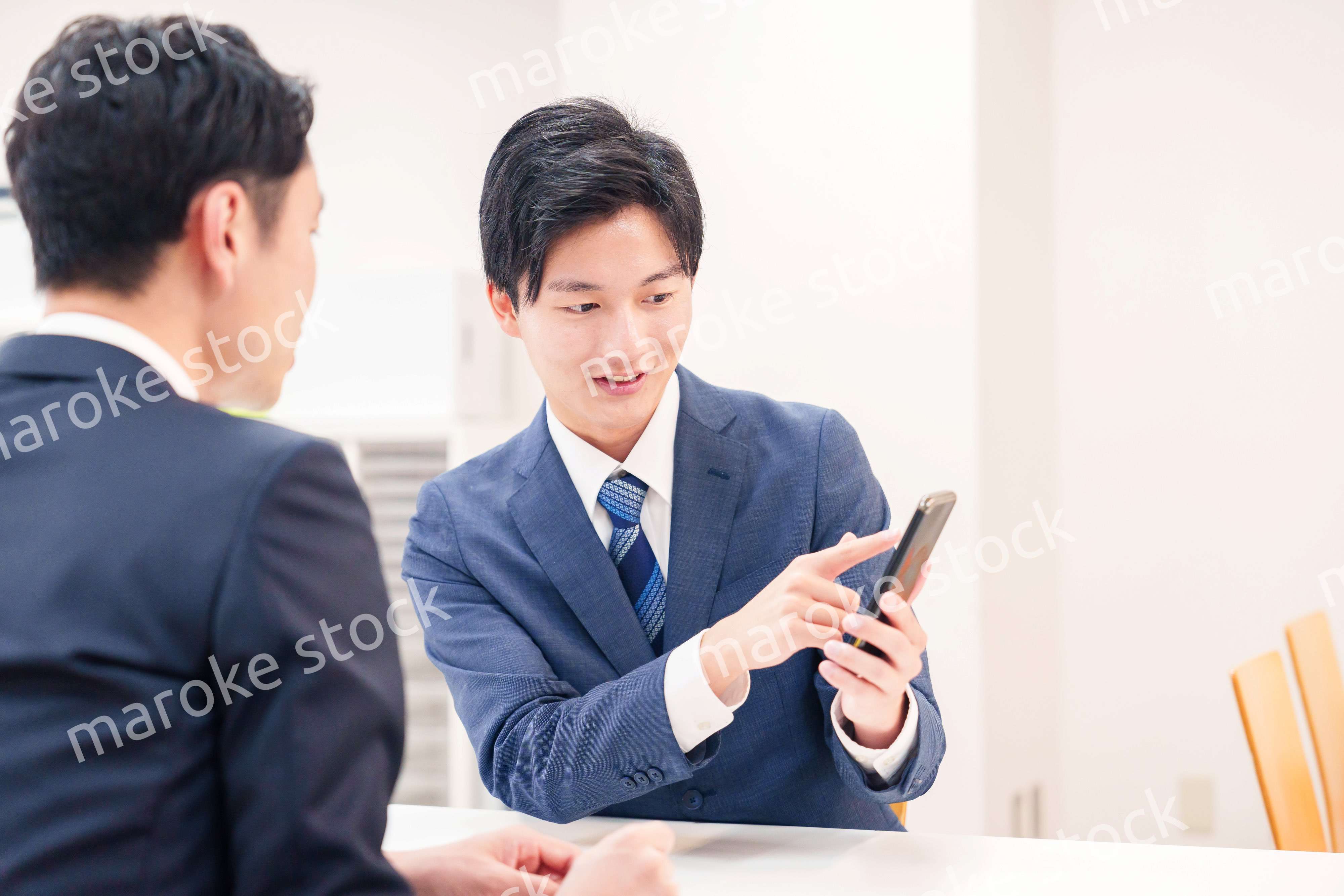 スマホを持って話をする二人のビジネスマン