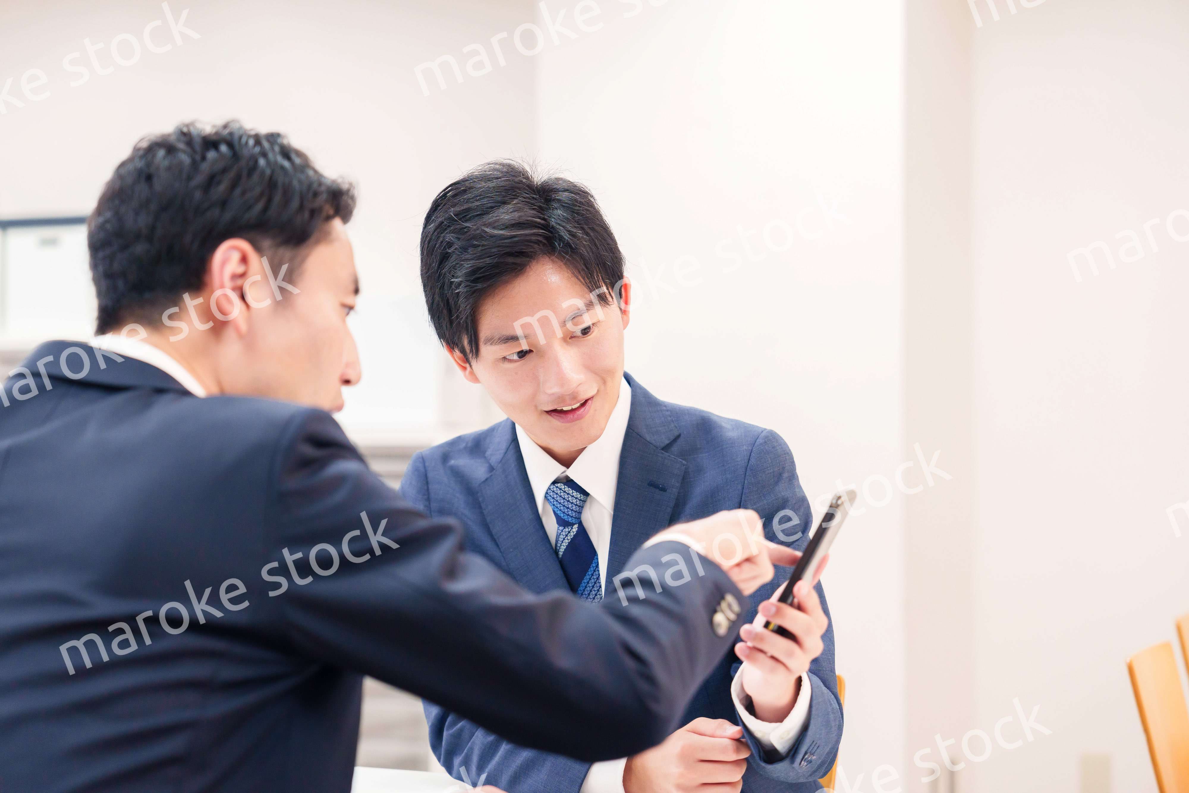 スマホを持って話をする二人のビジネスマン