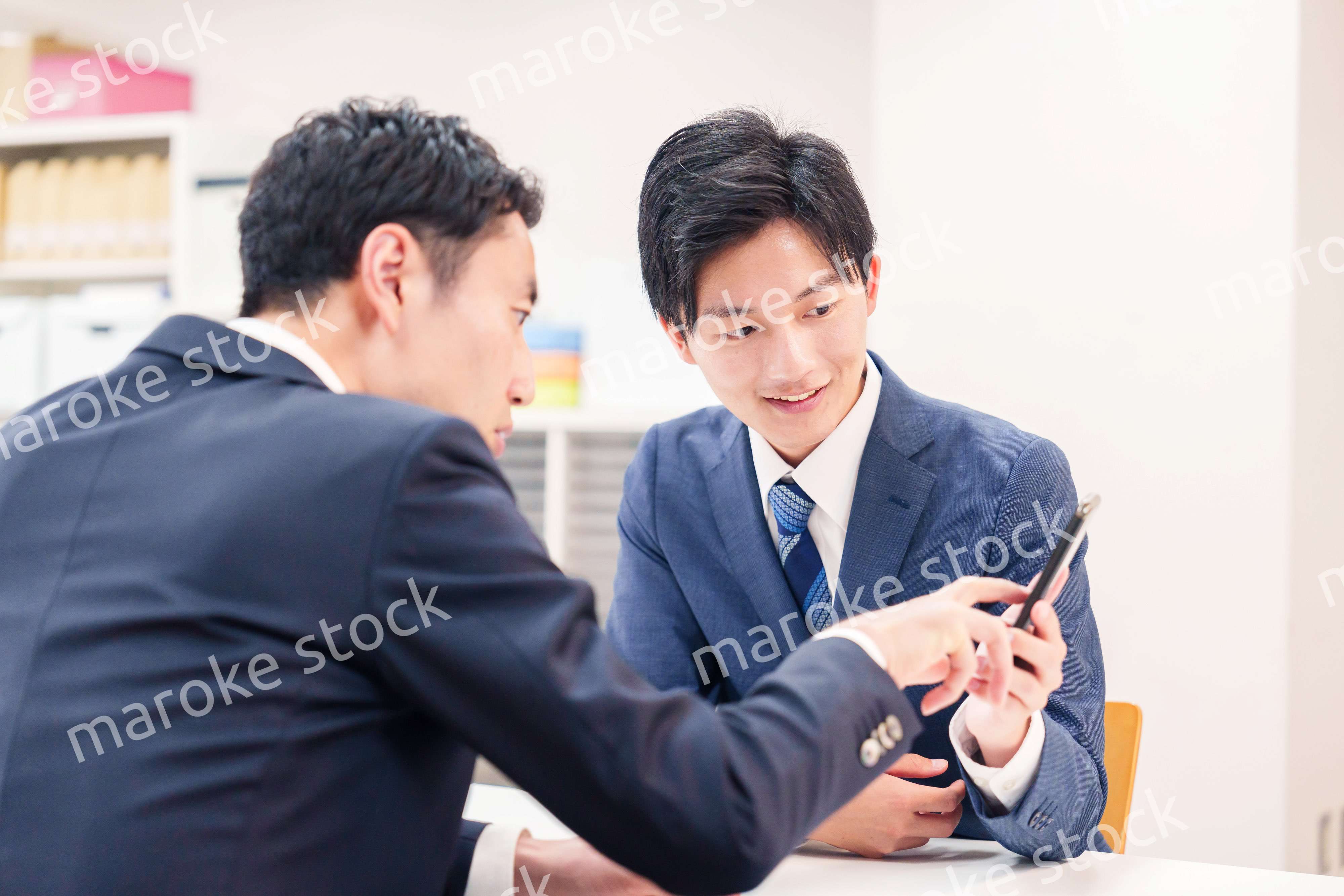スマホを持って話をする二人のビジネスマン