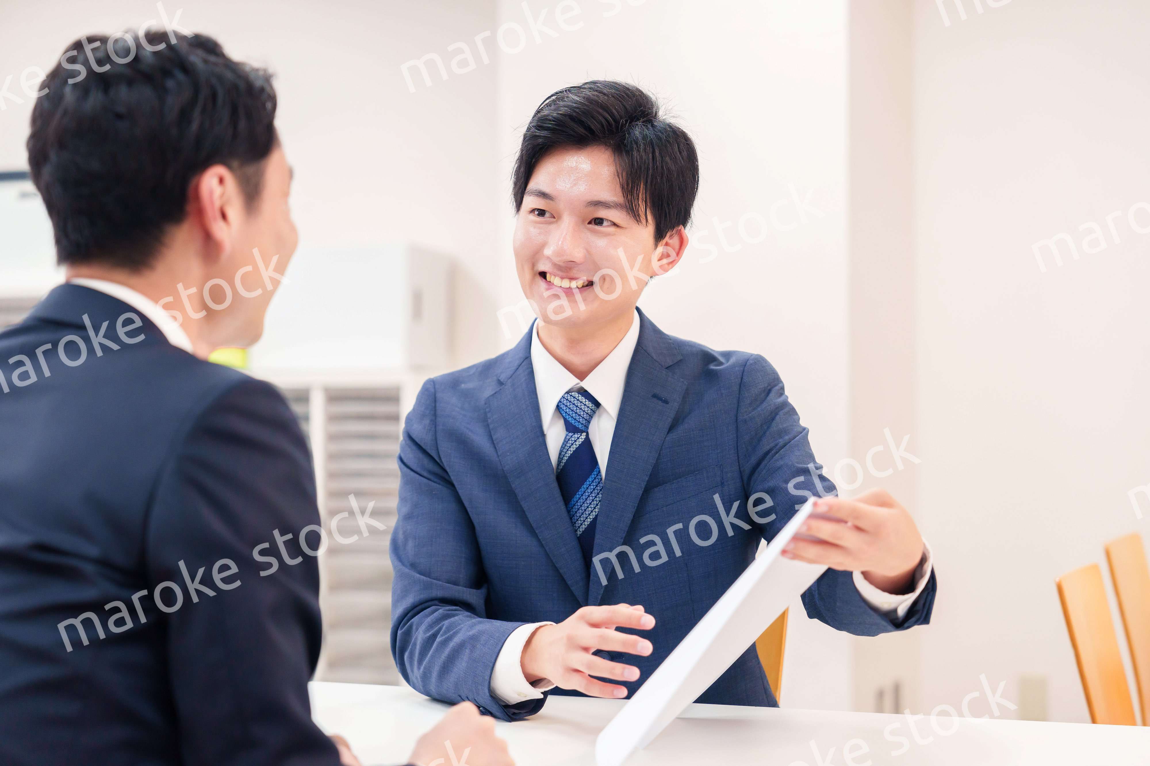 窓口で来客の対応をするビジネスマン