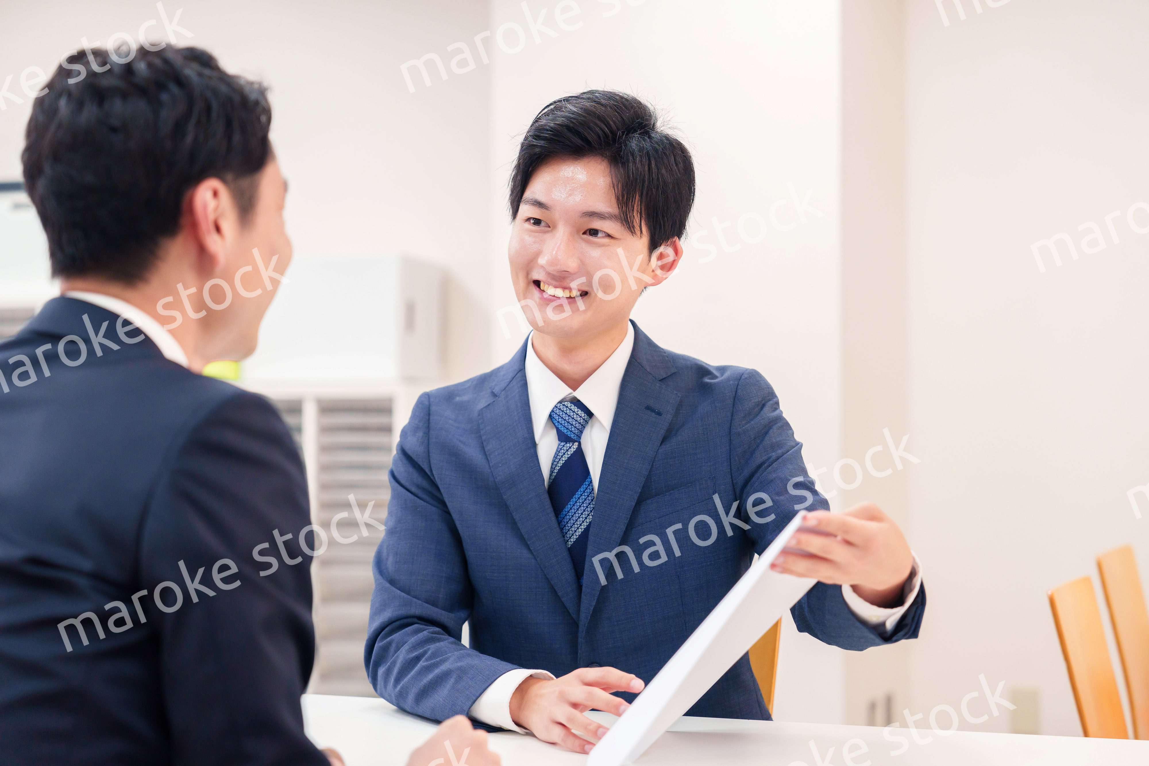 窓口で来客の対応をするビジネスマン