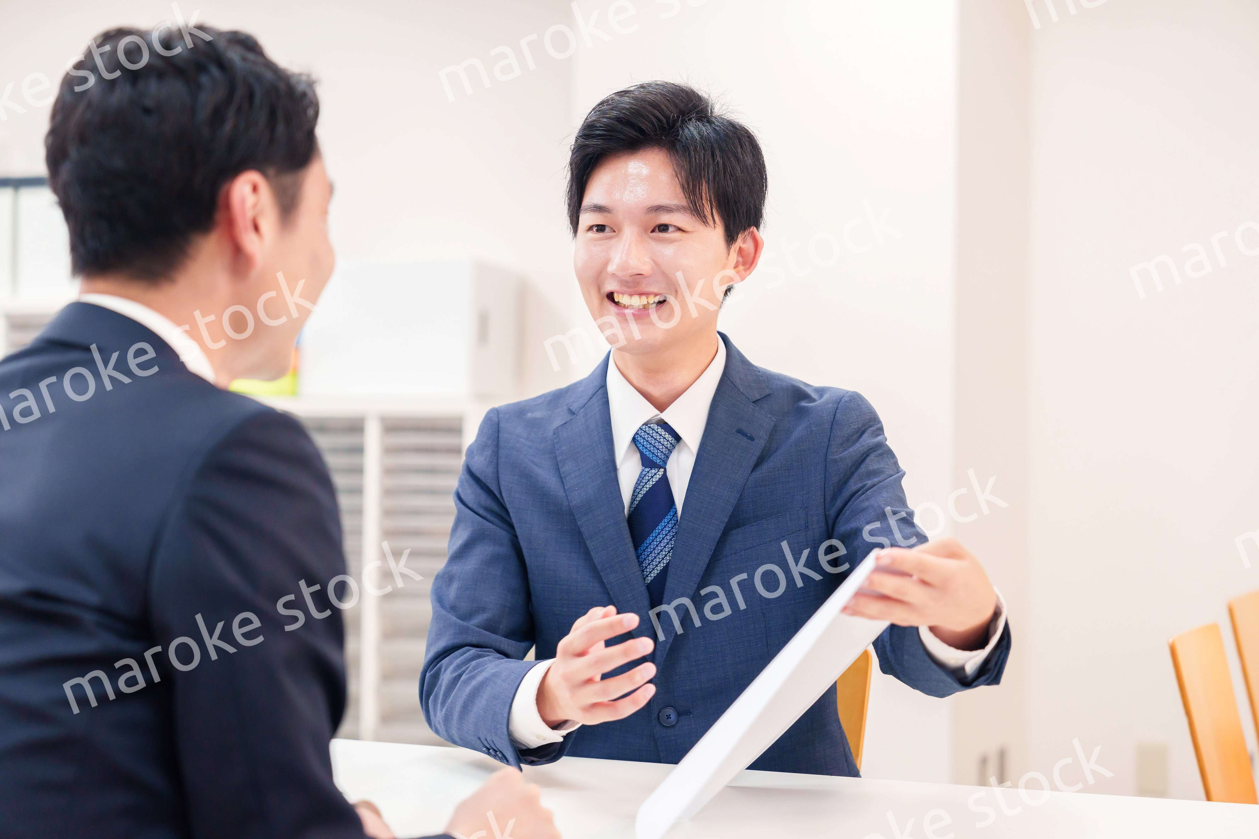 窓口で来客の対応をするビジネスマン