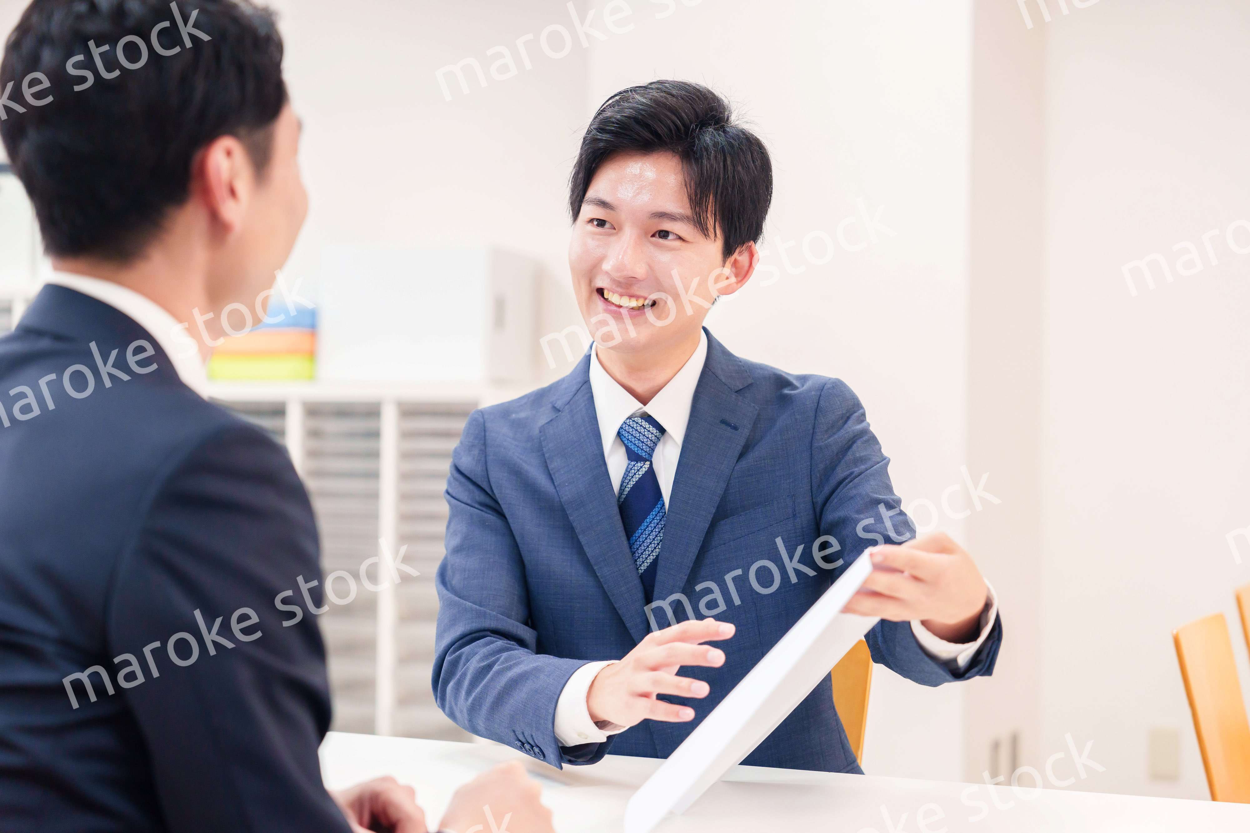 窓口で来客の対応をするビジネスマン