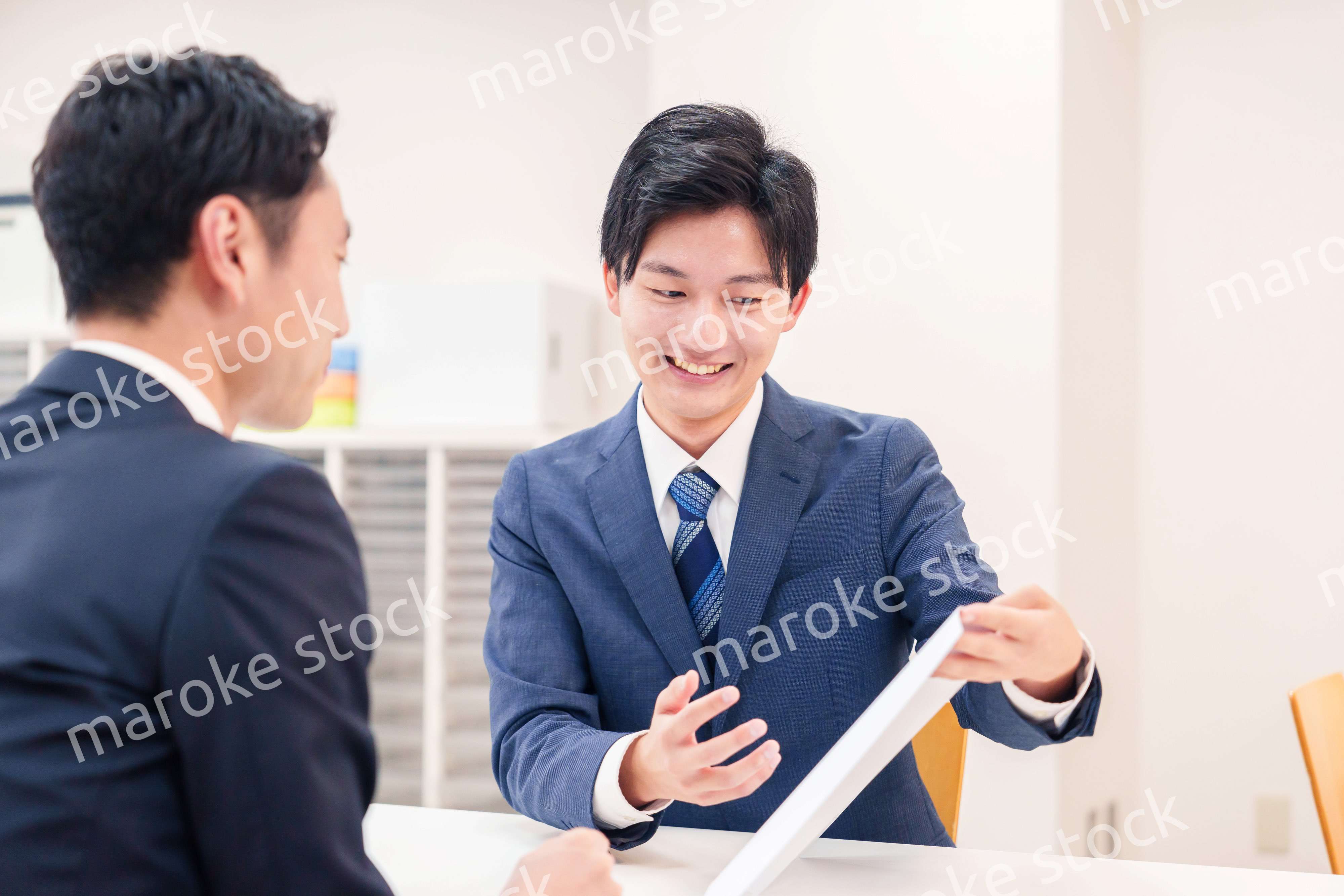 窓口で来客の対応をするビジネスマン